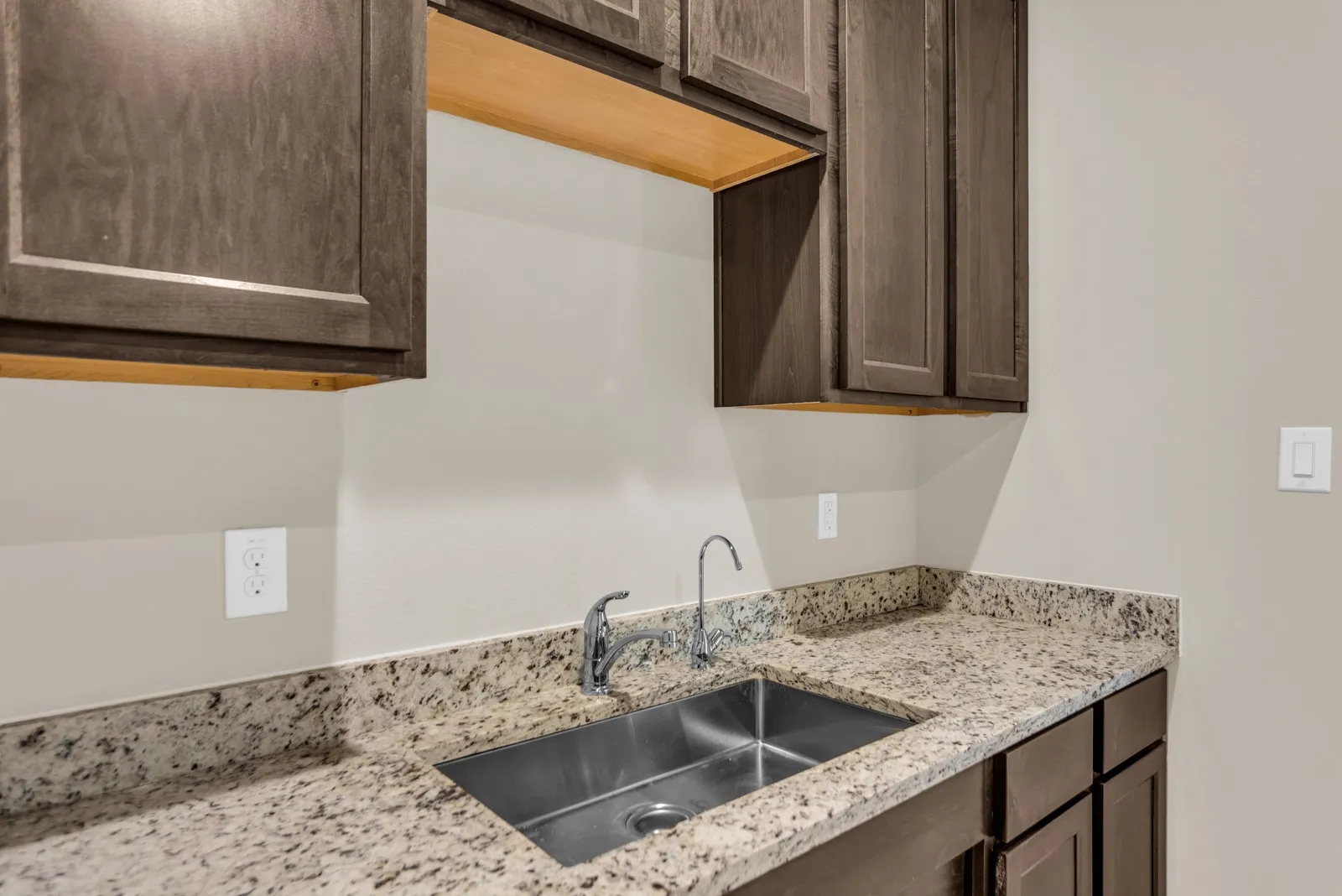 Granite-style countertop with an undermount stainless steel sink and gooseneck faucet