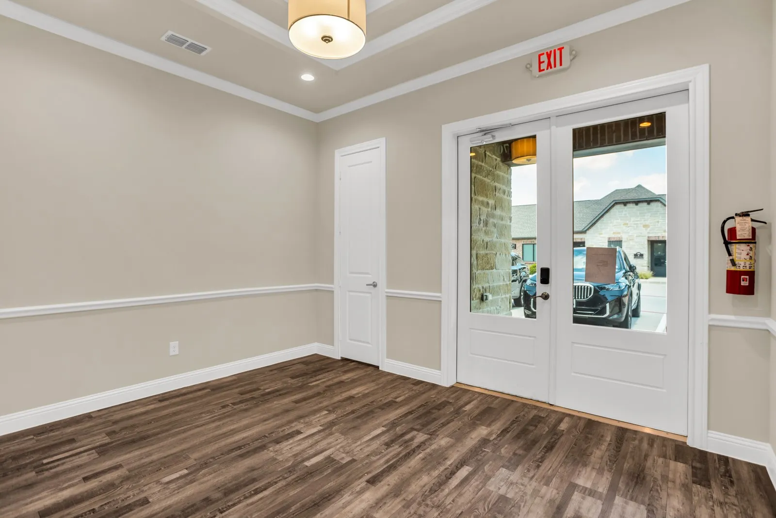 Wood-finish flooring, full-light French doors, recessed lighting, crown molding, and wainscoting