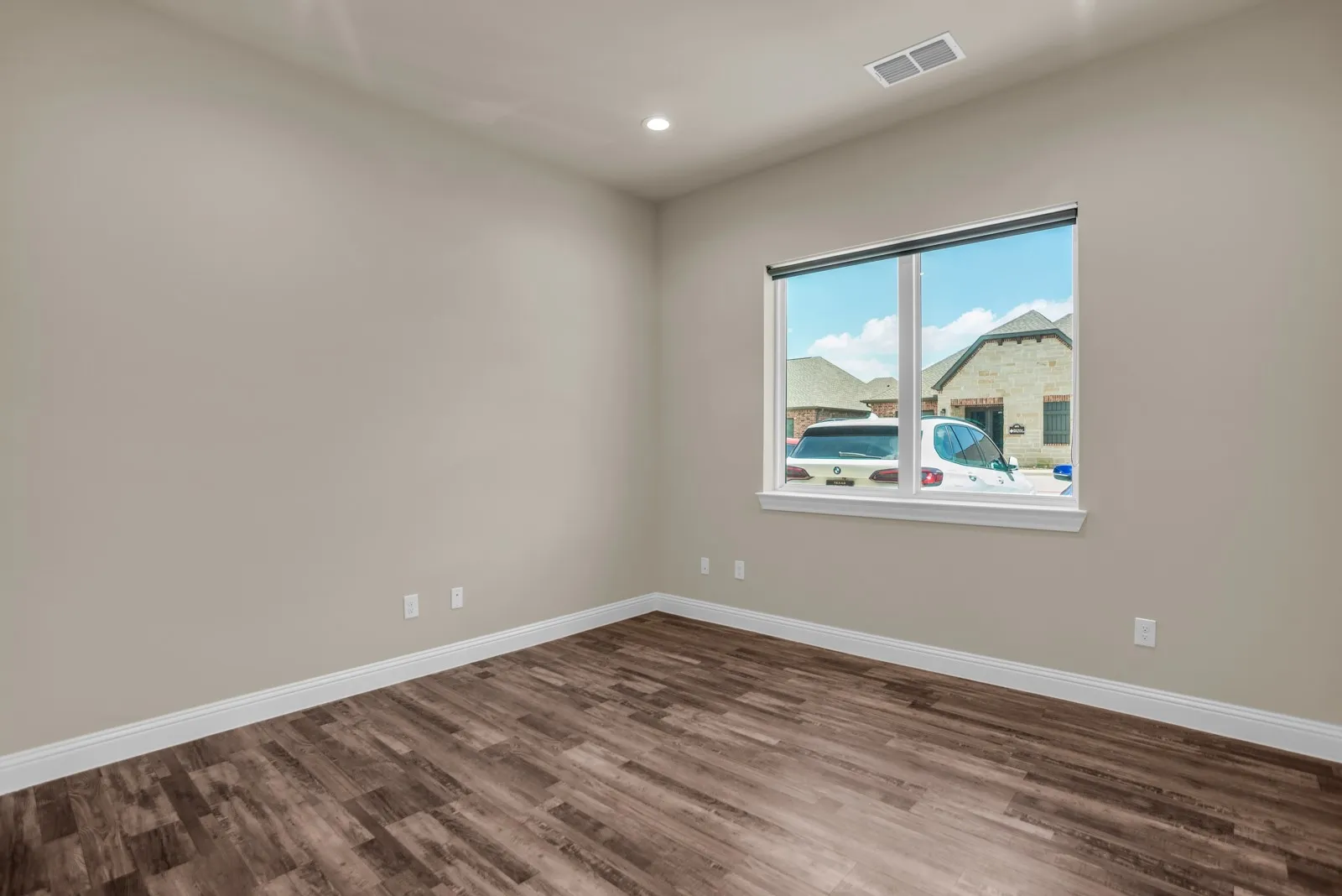 Wood-finish flooring, recessed ceiling light, and a large window with white trim
