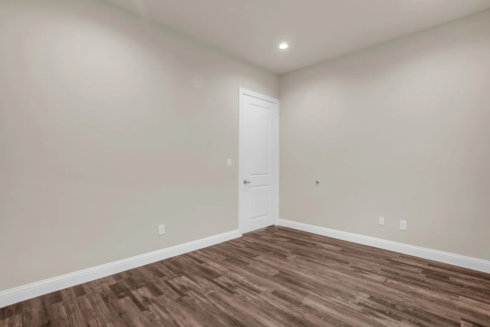 Recessed lighting, wood-finish flooring, white trim, and a paneled door