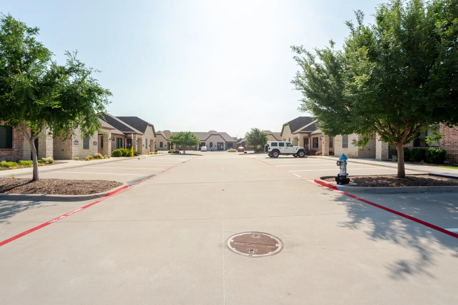Paved parking area featuring mature trees and landscaped islands