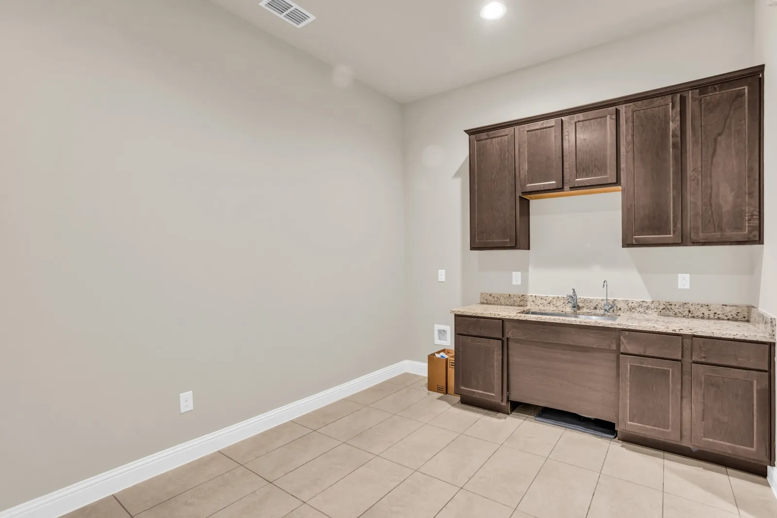 Wall-mounted cabinetry, granite countertops, undermount sink, and tile flooring