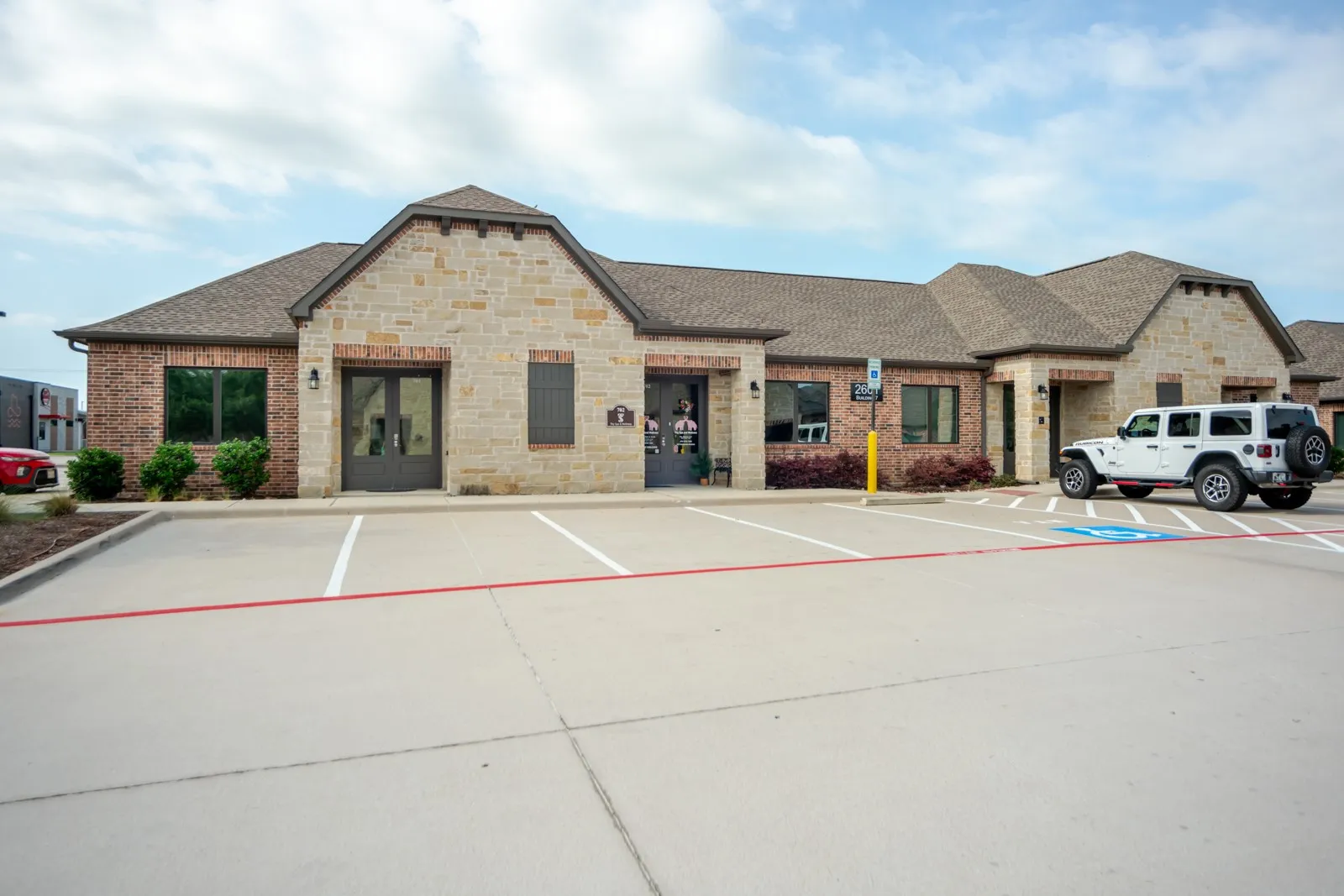 Masonry and brick exterior with a gabled roofline, double entry doors, and an asphalt parking lot