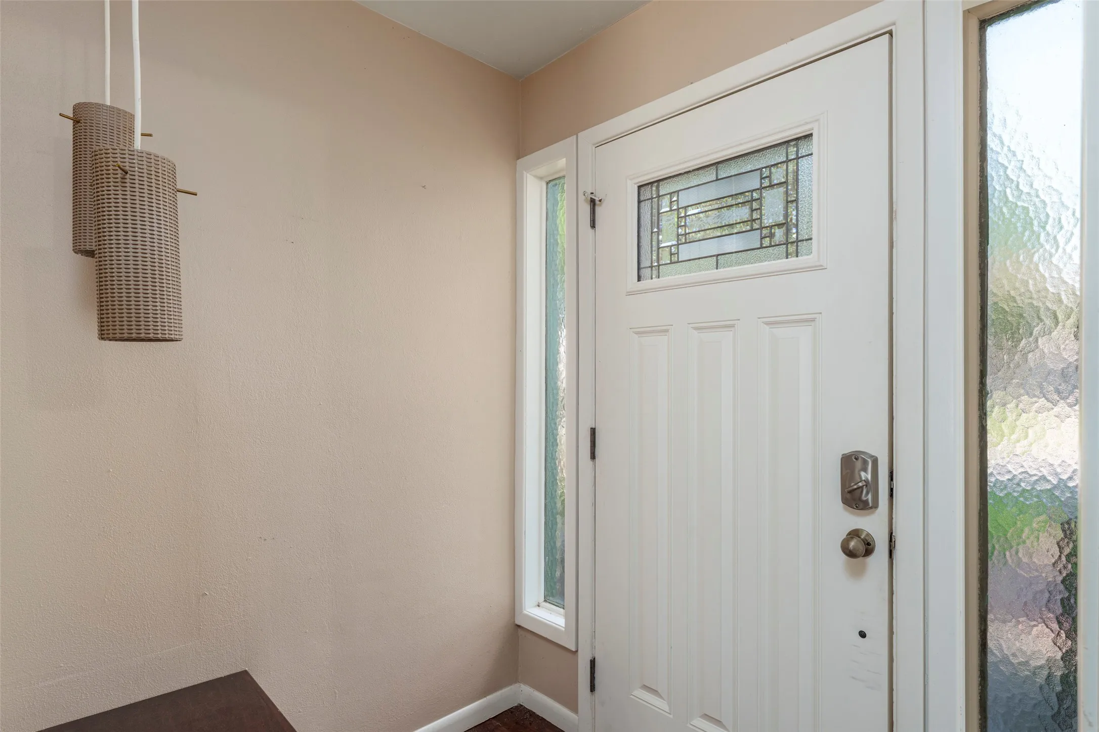 White entry door with leaded glass insert, flanked by two textured glass sidelights, and complemented by a modern pendant light fixture