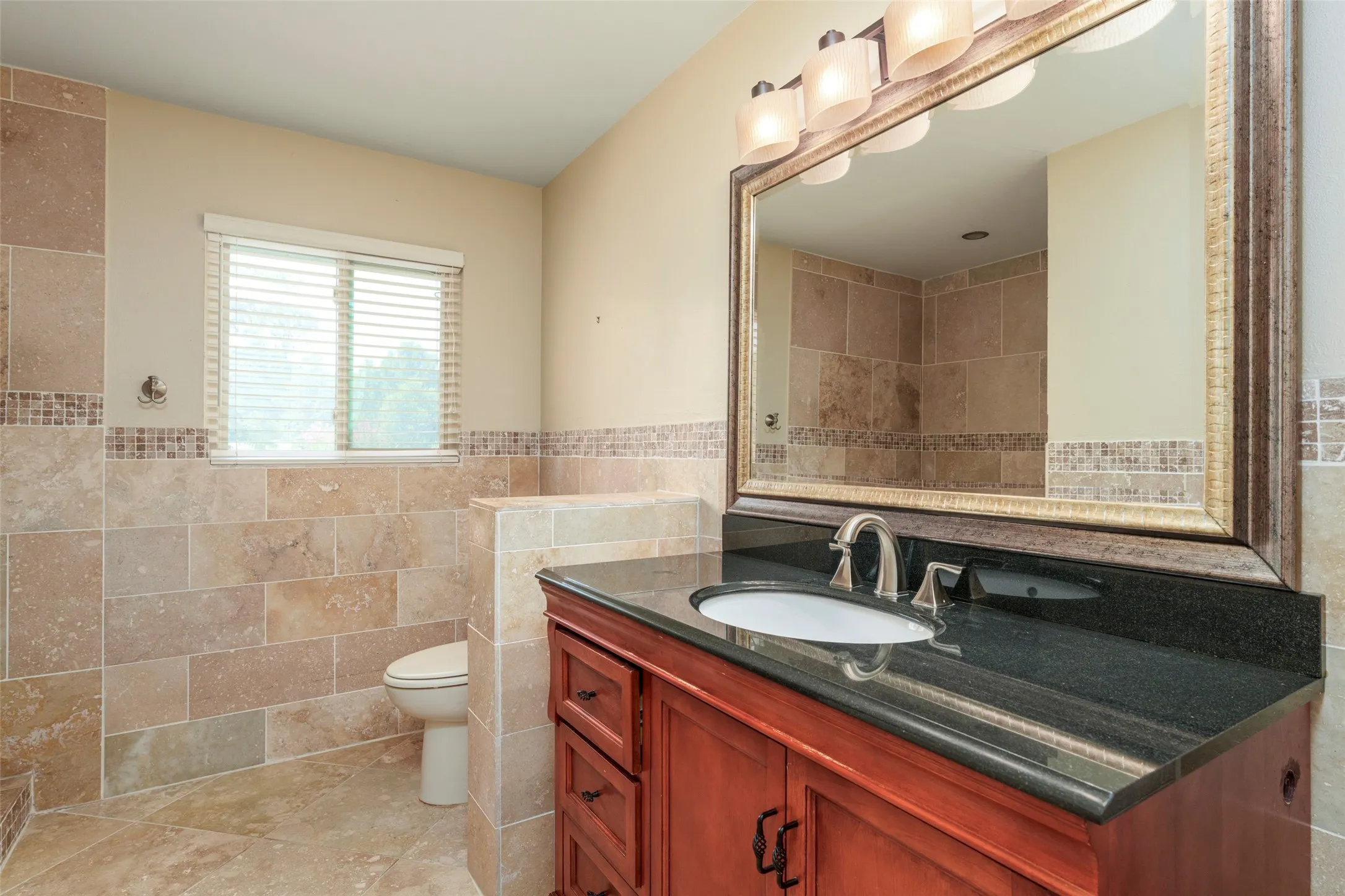 Cherry wood-finish vanity with a dark countertop and integrated sink