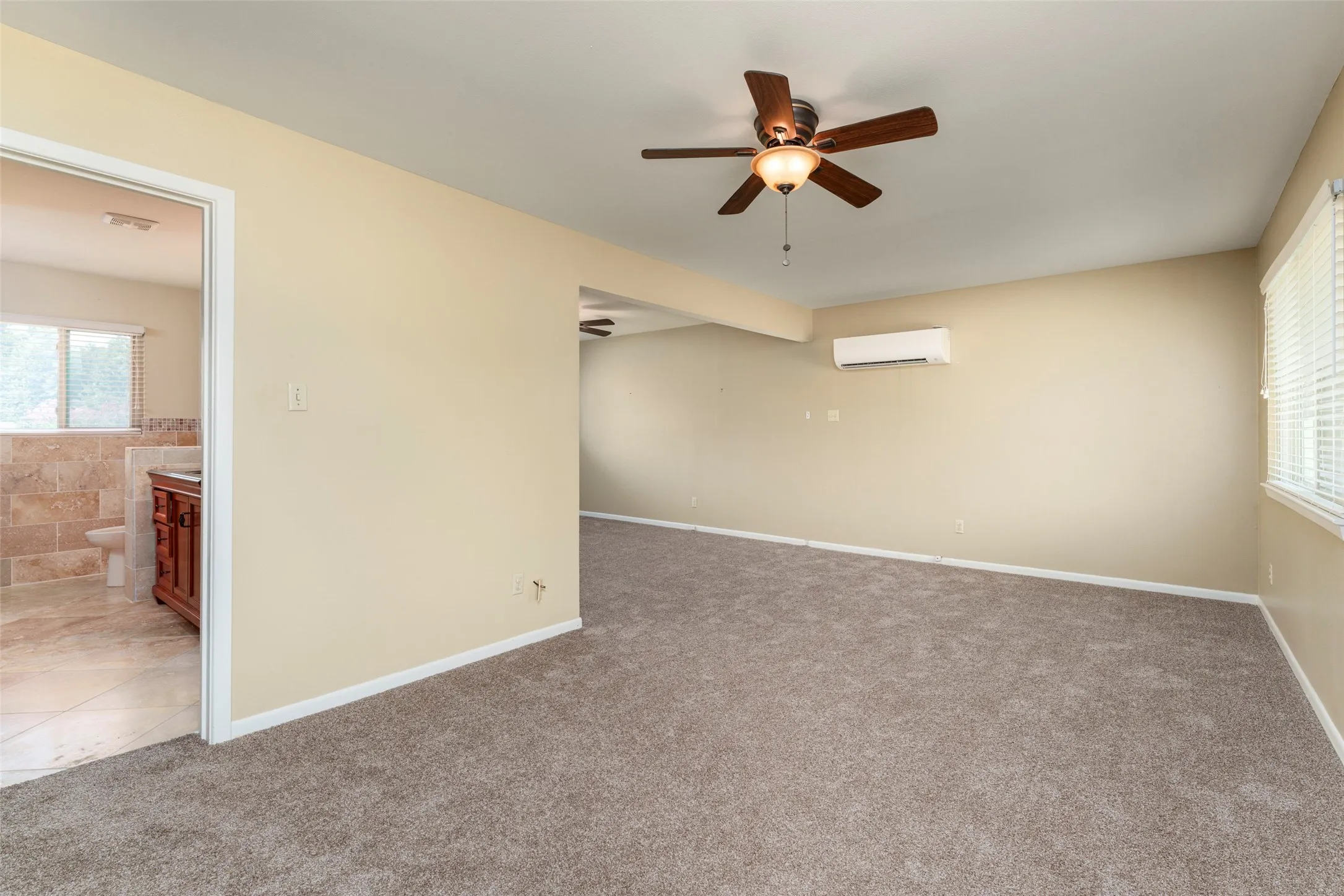Spacious room featuring carpeting, a ceiling fan with integrated lighting, and an installed air conditioning unit