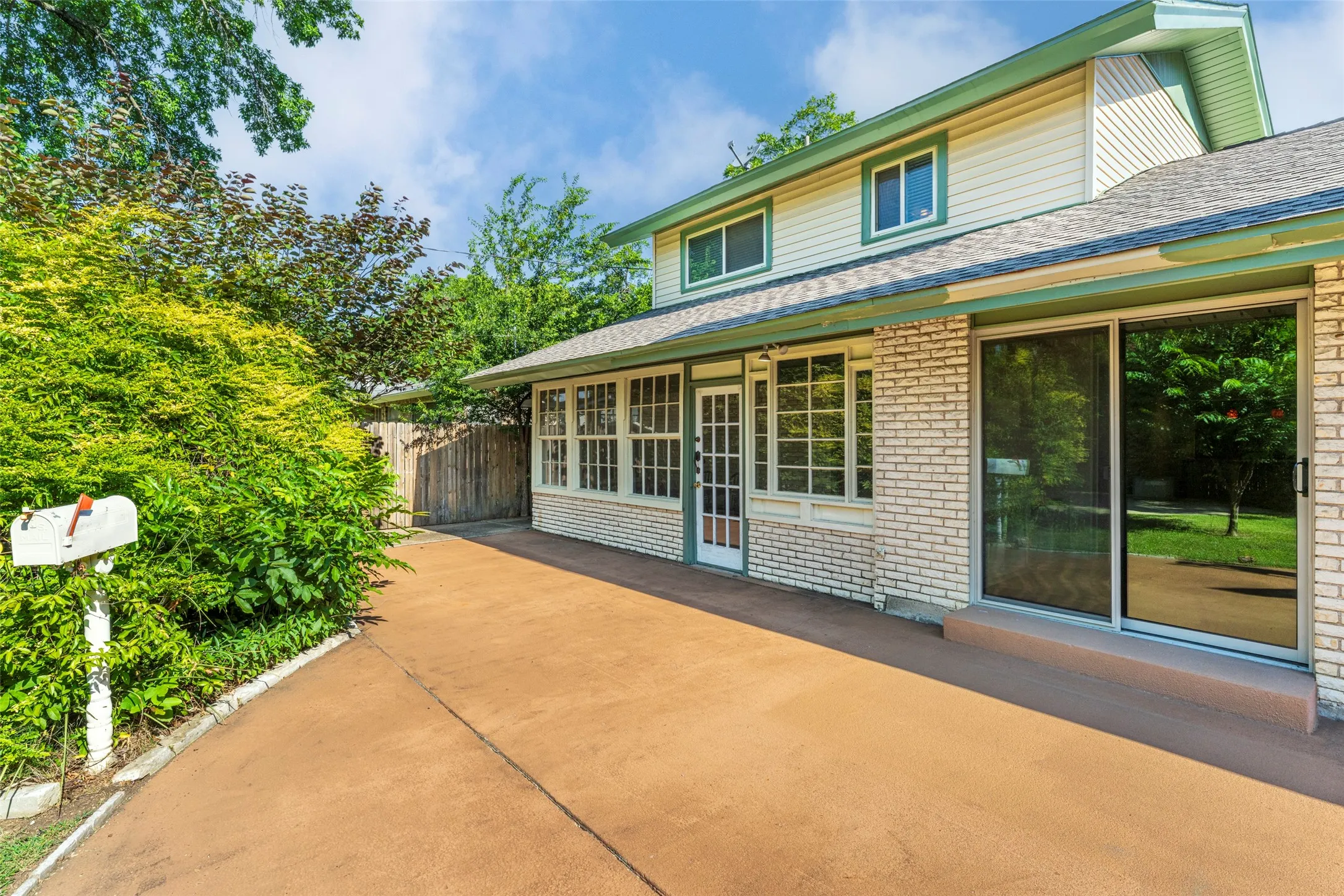 Two-story exterior with light-toned brick and siding, featuring a substantial paved driveway