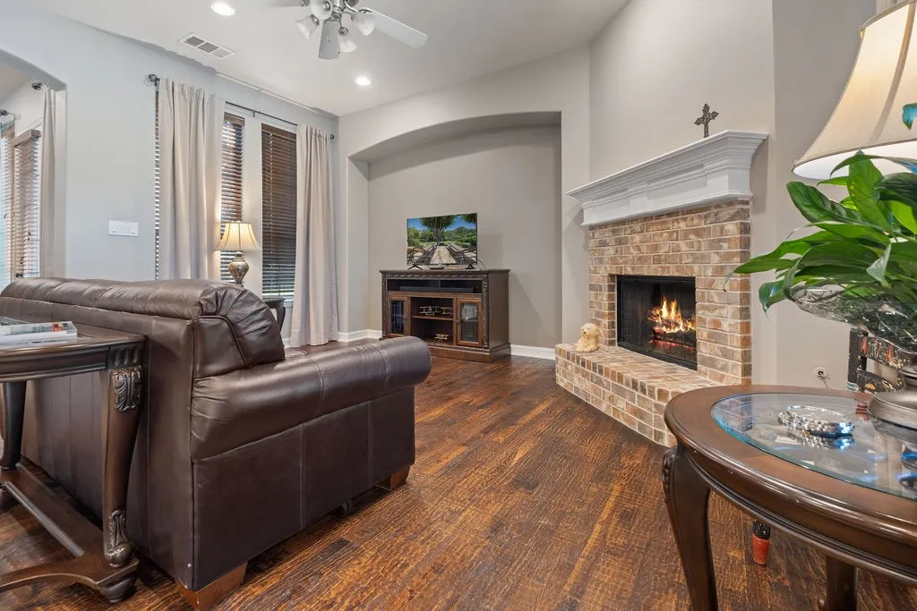 Living space featuring wood-finish flooring, a brick fireplace with a white mantel, recessed lighting, and a ceiling fan
