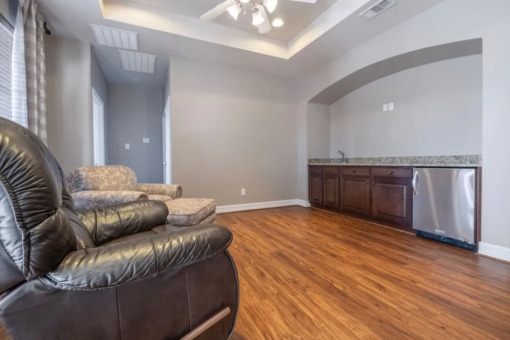 Luxury vinyl plank, trey ceiling, ceiling fan, arched alcove with built-in cabinetry, stainless steel beverage refrigerator, and​​‌​​​​‌​​‌‌​‌‌​​​‌‌​‌​‌​‌​​​‌​​ sink