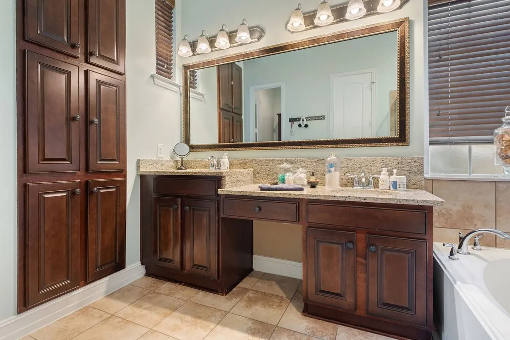 Double vanity with light-toned countertop, framed mirror, and built-in storage cabinetry