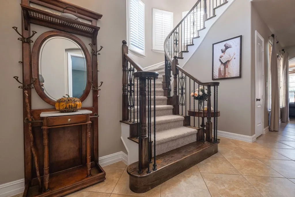 Curved staircase with carpeted treads and wrought iron balusters