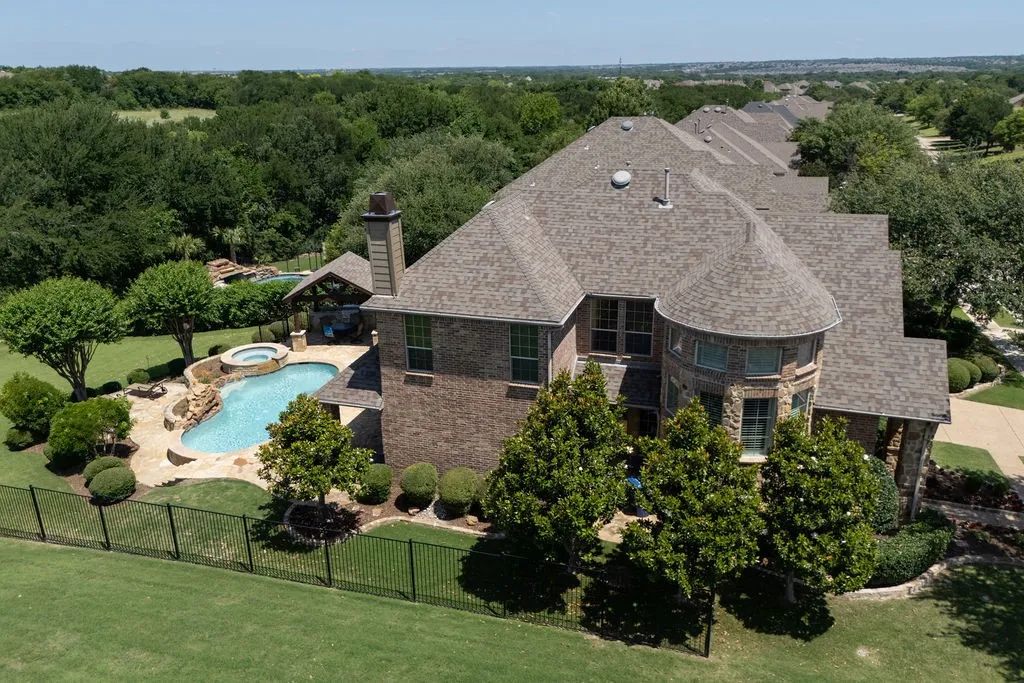 Brick and stone exterior with a turret, multi-level roofline, pool with integrated spa, and an outdoor covered entertaining area