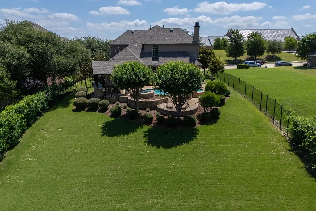 Expansive grassy yard with a black metal fence