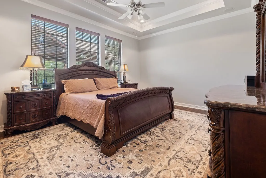 Three large windows with blinds, tray ceiling with a ceiling fan, and tile flooring