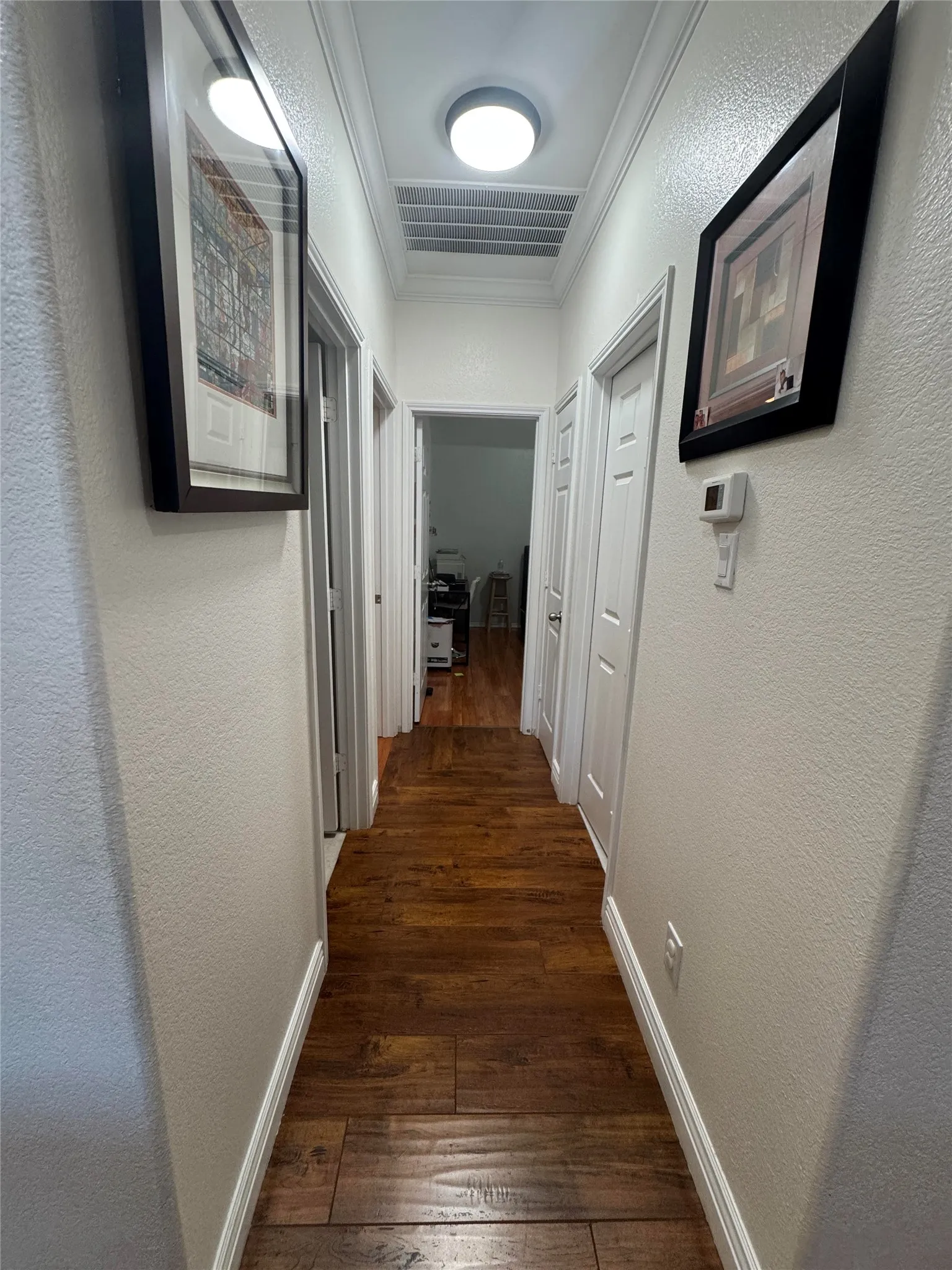 Hallway featuring wood-finish flooring, white walls, white trim, and flush-mount lighting