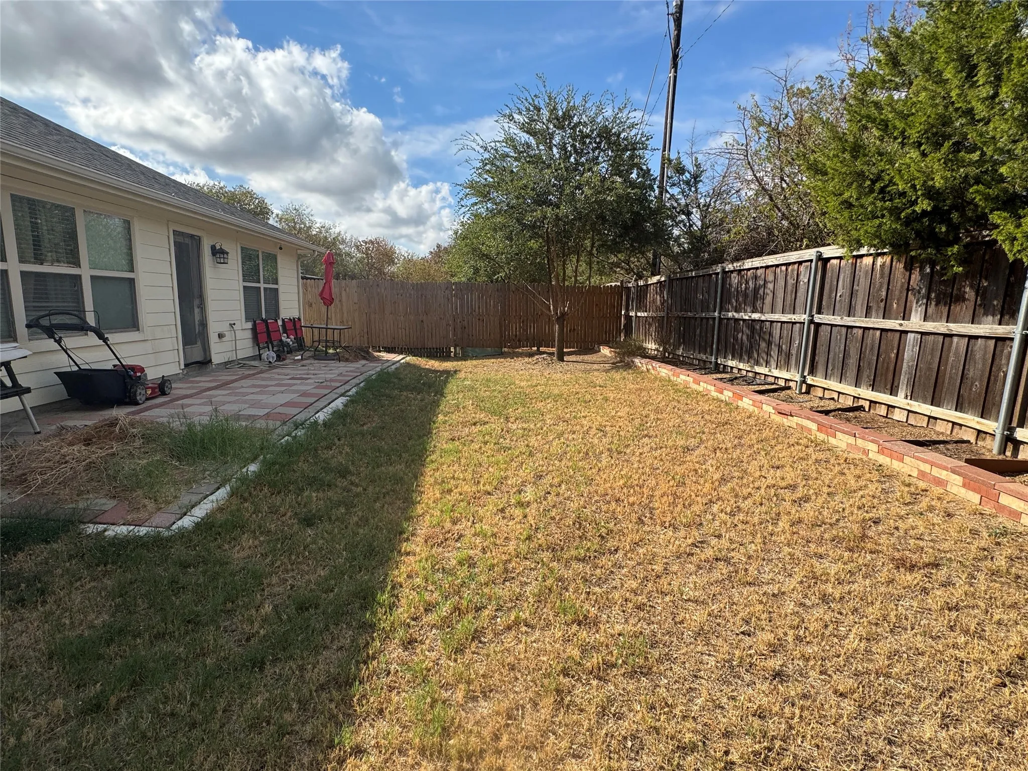 Fenced backyard with a paver patio and a raised brick planting bed
