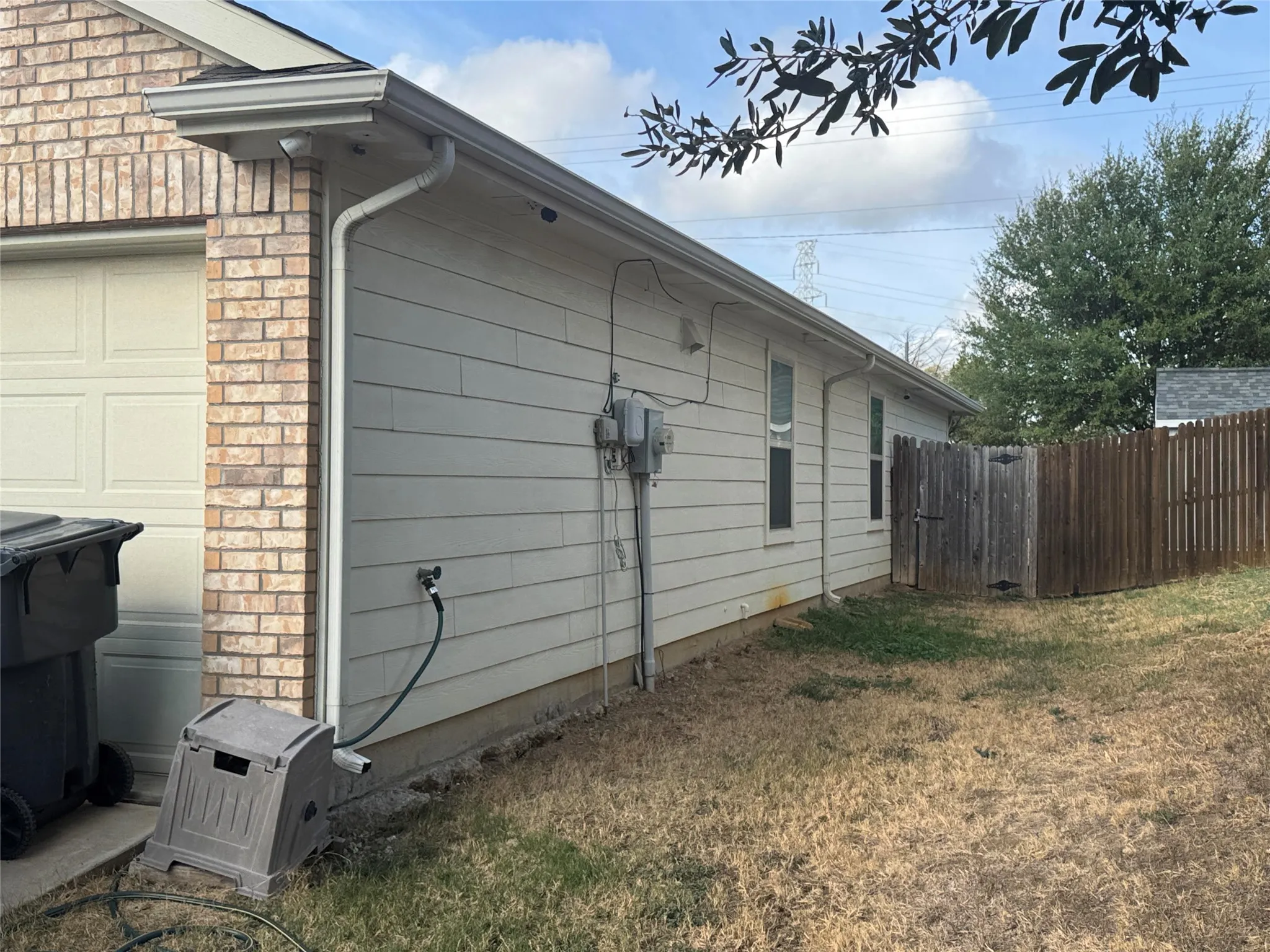 Brick veneer exterior with horizontal siding, a two-car garage door, and a wooden privacy fence