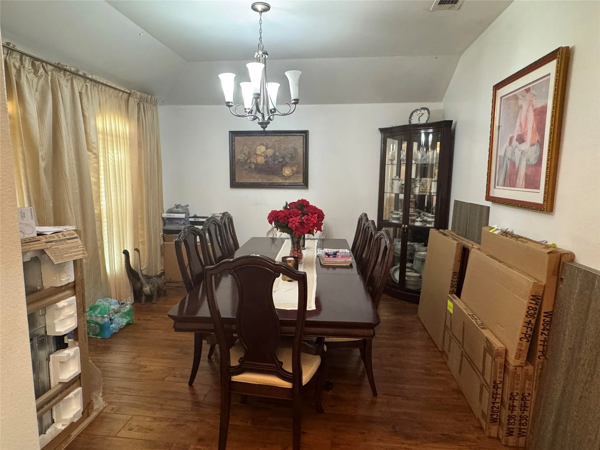 Tray ceiling with a central chandelier above wood-finish flooring