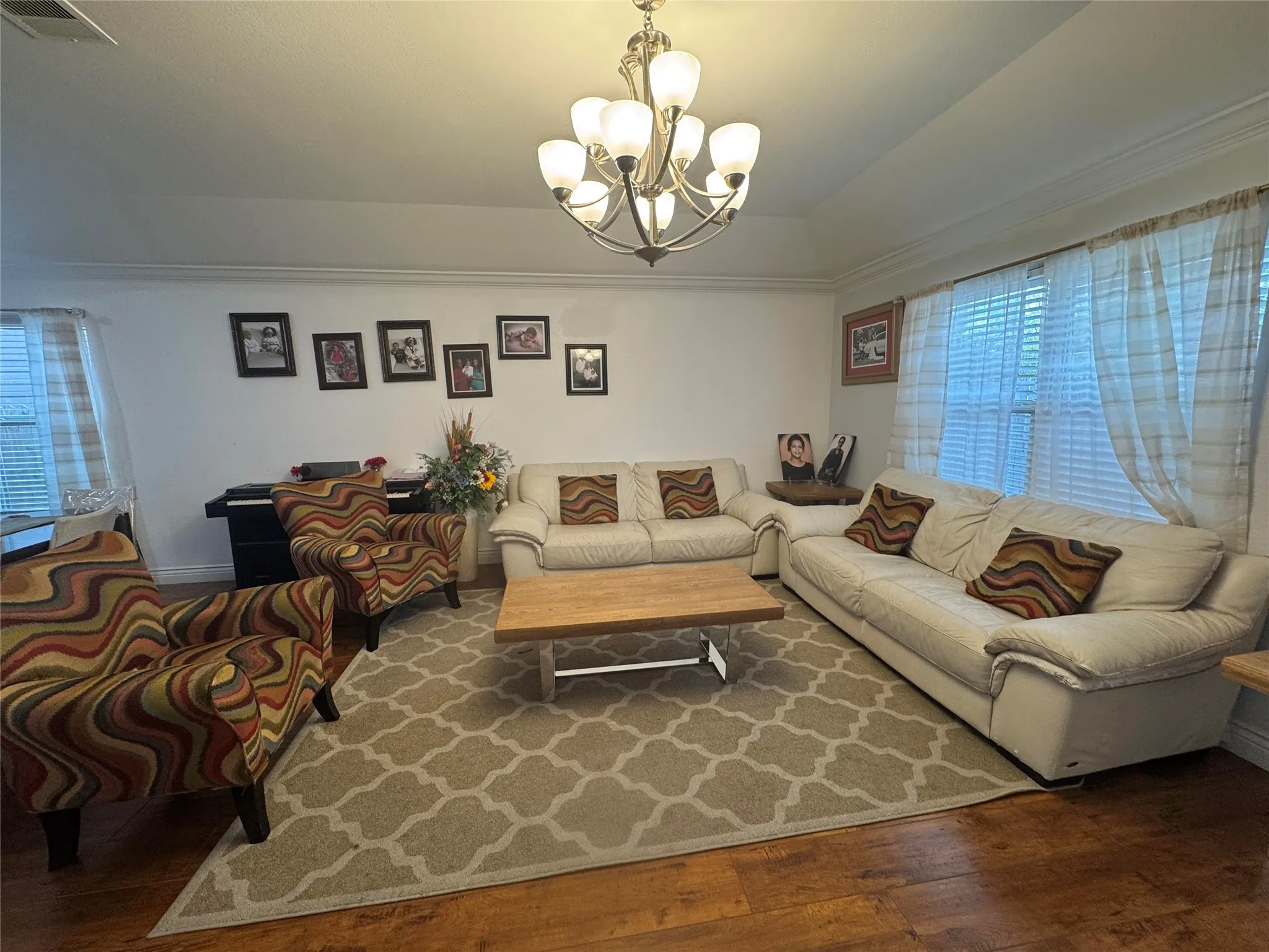 Hardwood-finish flooring, crown molding, vaulted ceiling, and a multi-light chandelier
