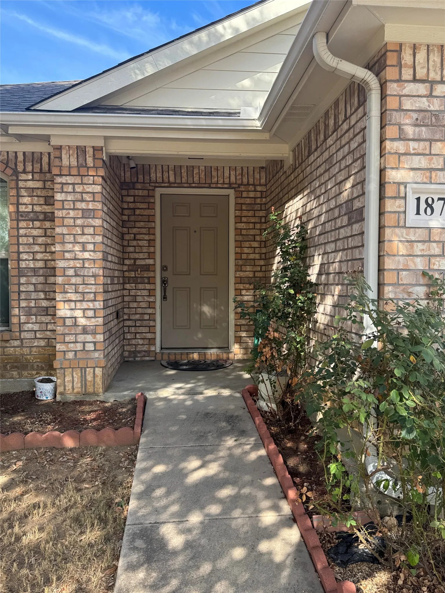Brick exterior with a covered entry and a solid panel front door