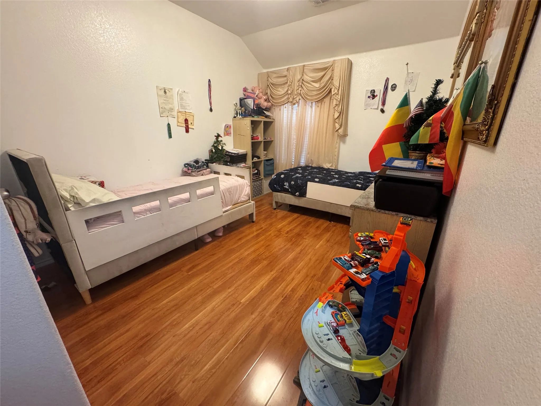 Recessed window with drapes, wood-finish flooring, and white painted walls
