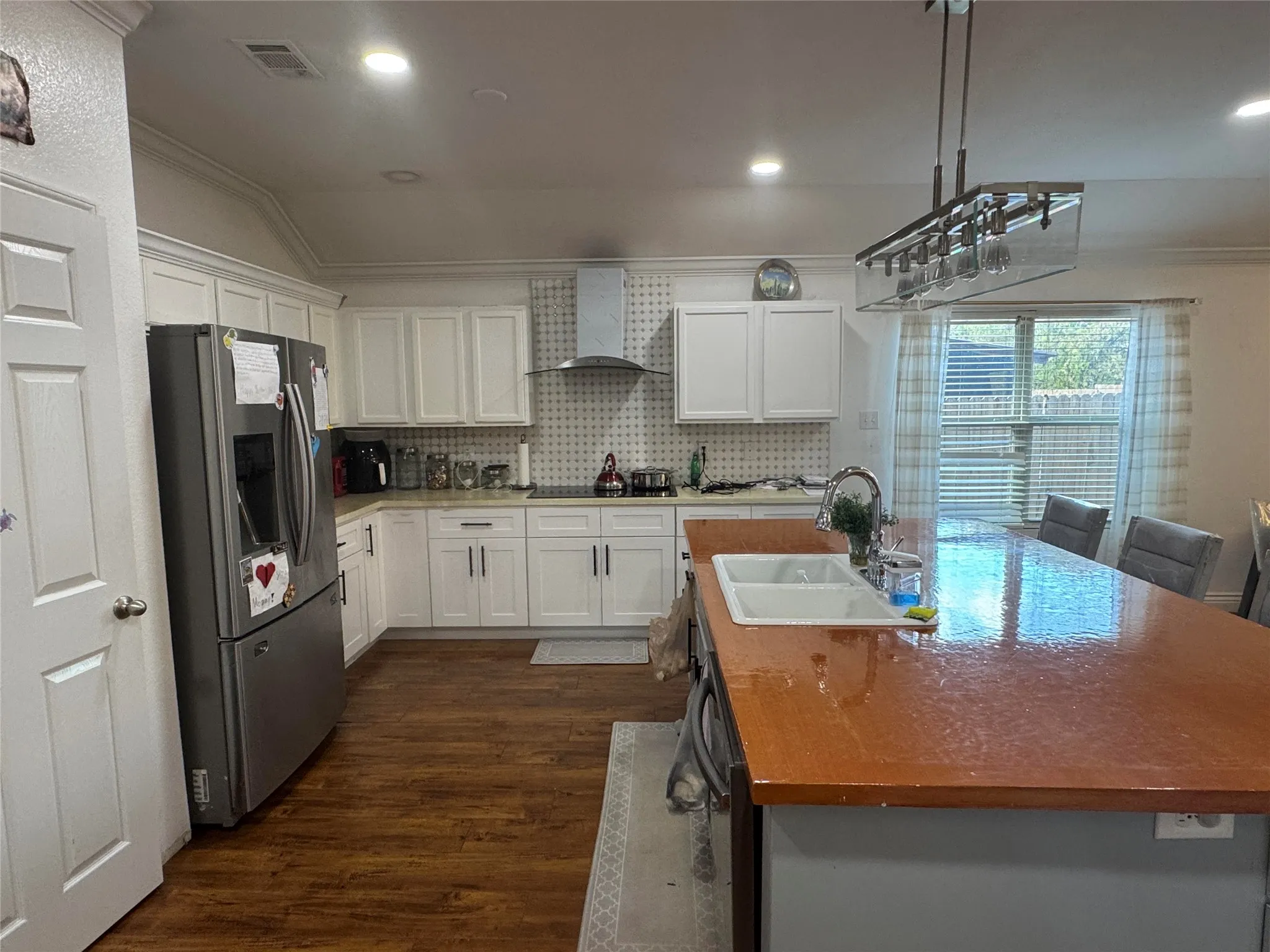 White shaker cabinetry with modern pulls, wood-finish flooring, recessed lighting, and a kitchen island with an integrated sink