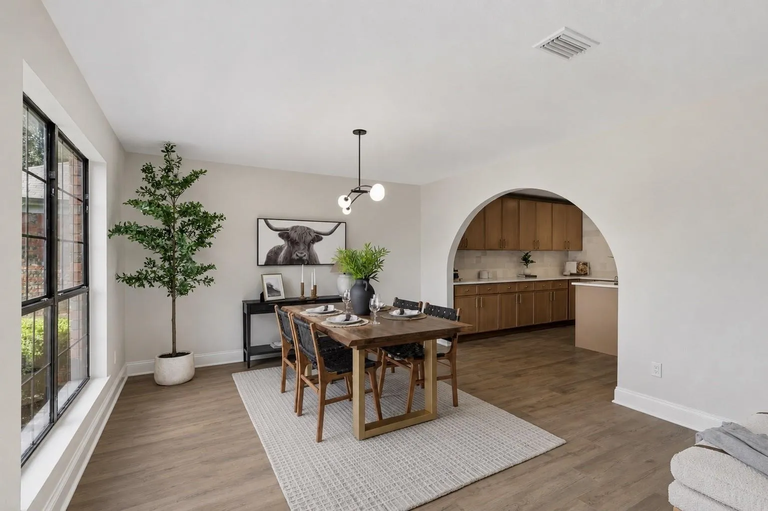 Spacious room featuring wood-finish flooring, a large multi-pane window, and an arched entry