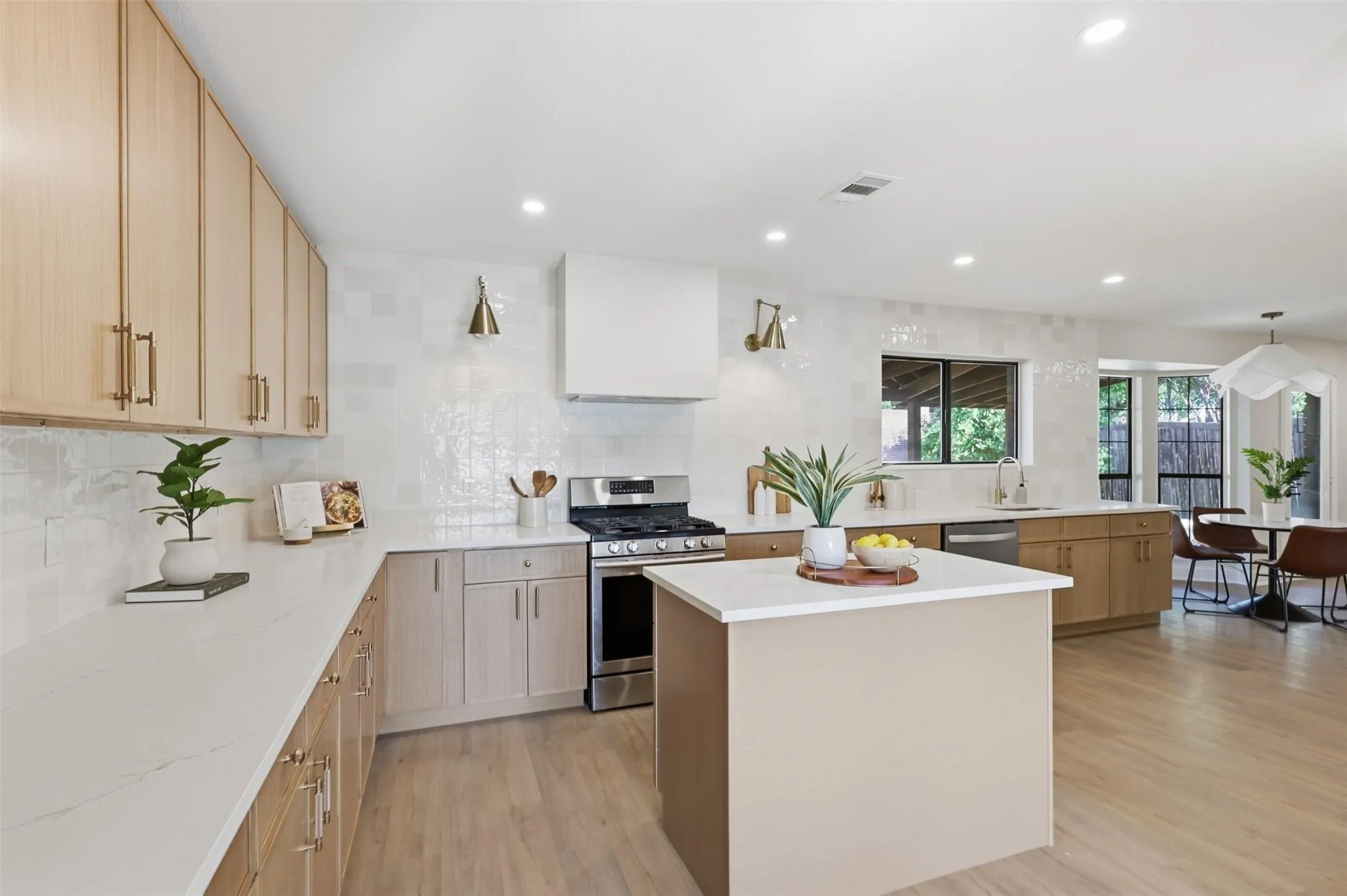 Spacious kitchen featuring a central island, light wood-finish cabinetry, stainless steel appliances, white countertops, and recessed lighting