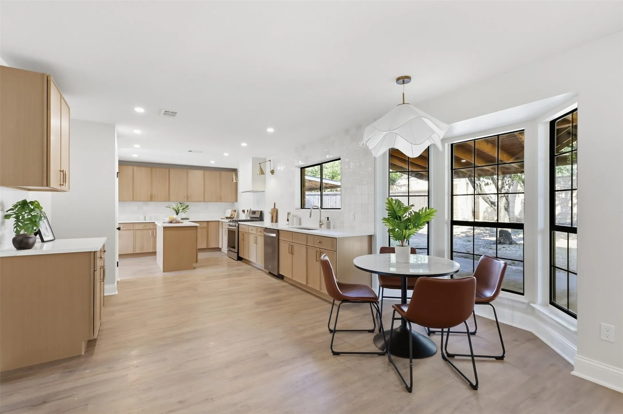 Spacious kitchen featuring light wood-finish cabinetry, white countertops, stainless steel appliances, and wood-finish flooring