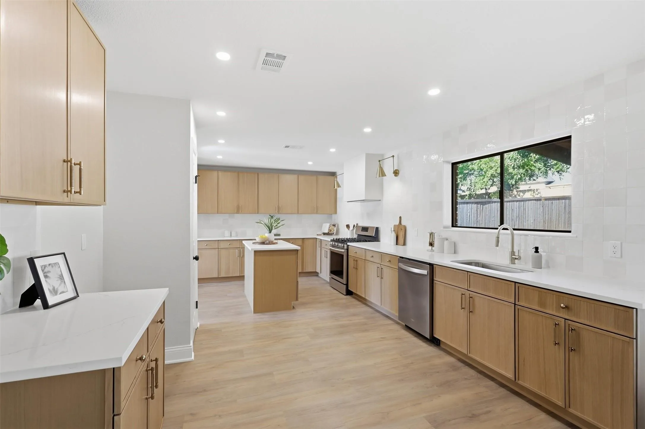 Kitchen featuring light wood-finish cabinetry, white countertops, a central island, and stainless steel appliances