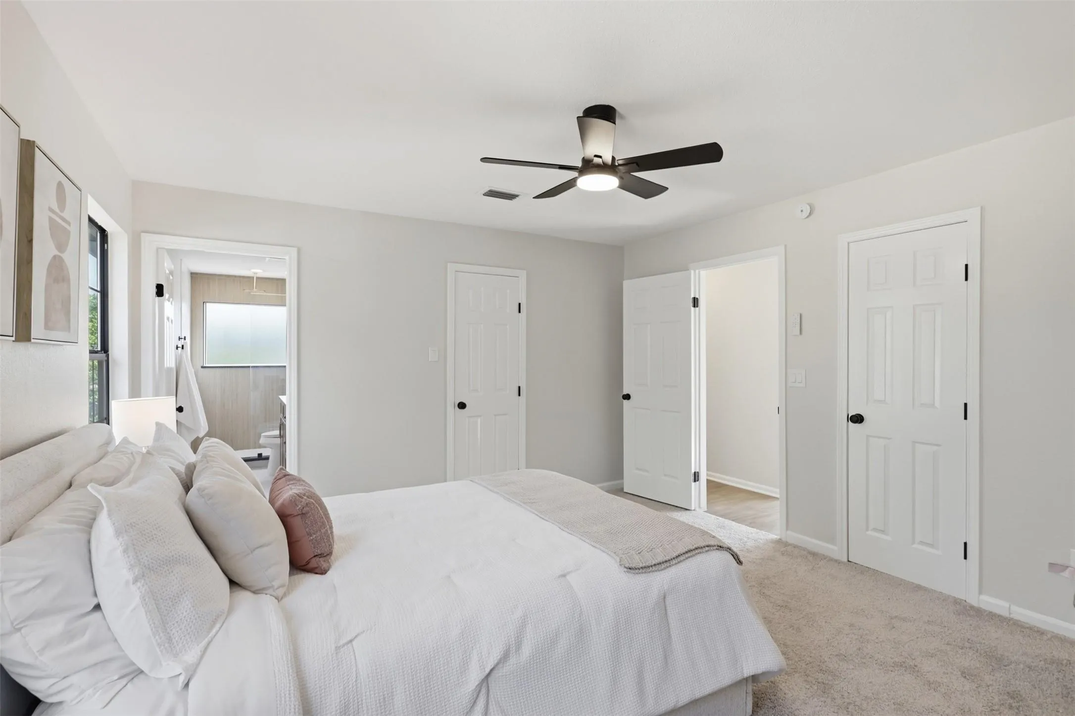 Master bedroom featuring neutral décor, ceiling fan with integrated lighting, multiple closets with six-panel doors, and carpeted flooring throughout