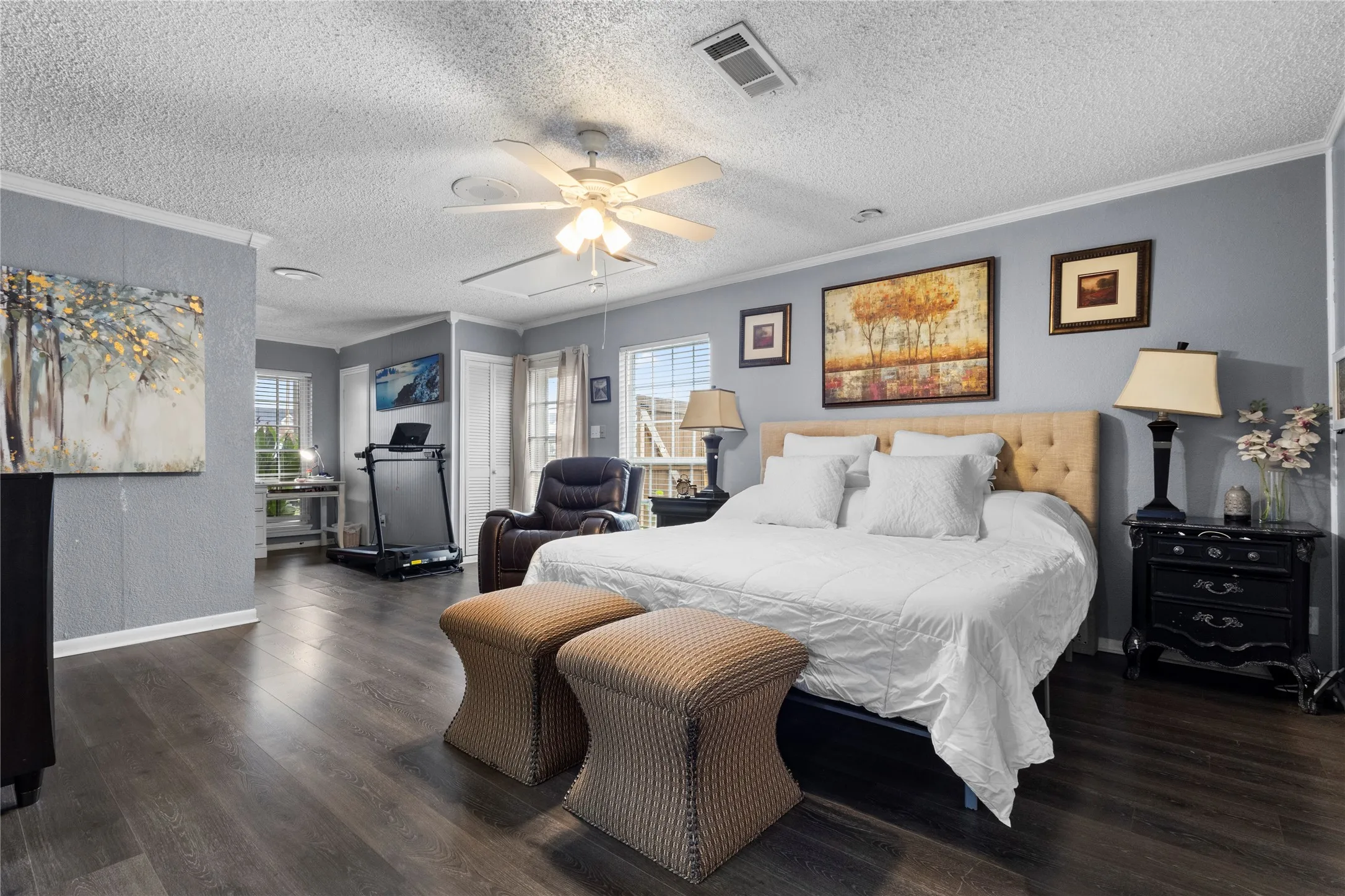 Spacious room with wood-finish flooring, light gray walls, white trim, and a ceiling fan