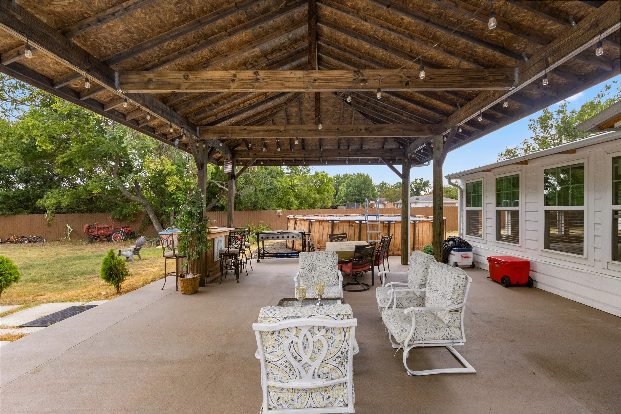 Expansive covered patio with exposed wood beams and string lighting
