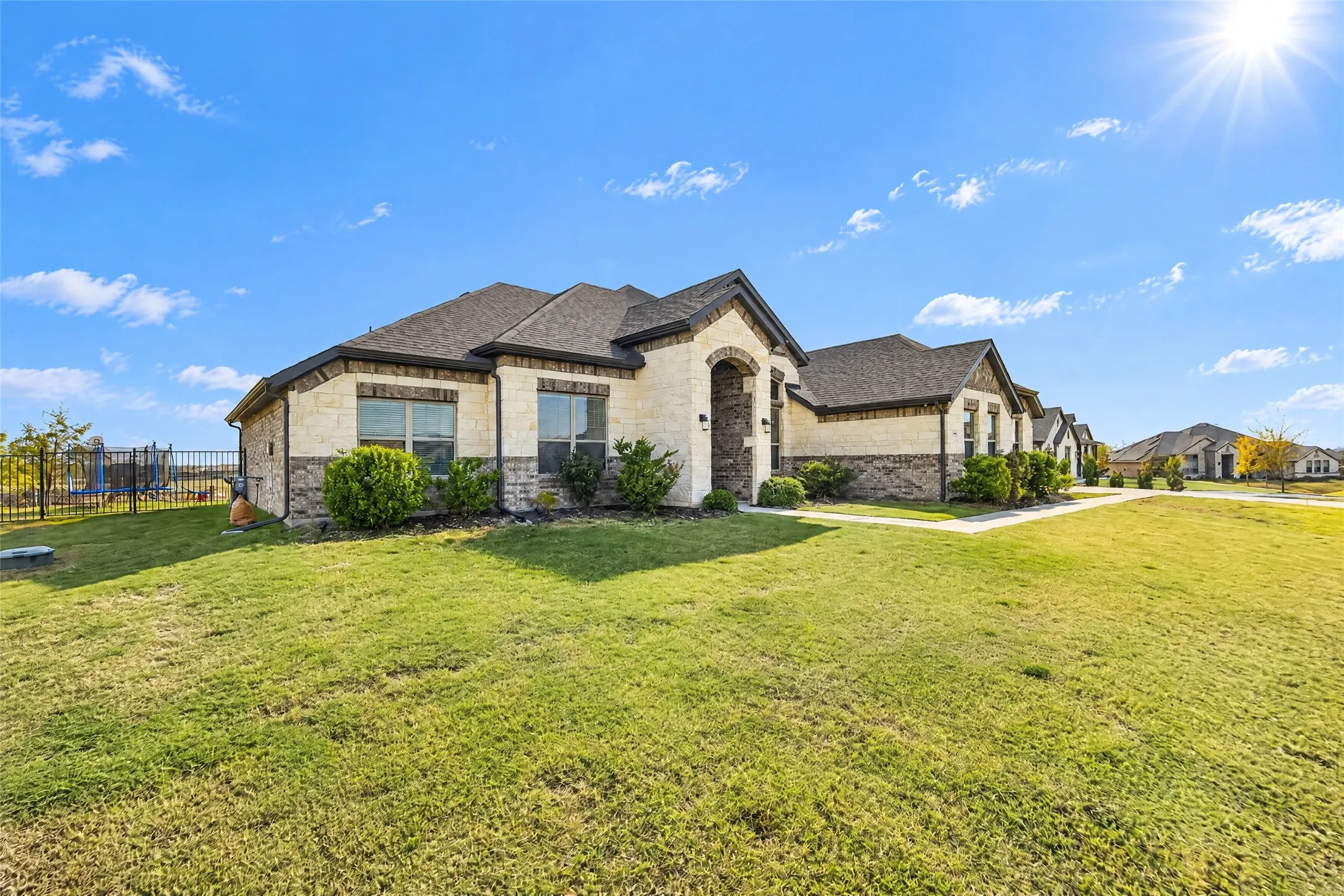 Stone and stucco exterior with dark trim and an arched entry