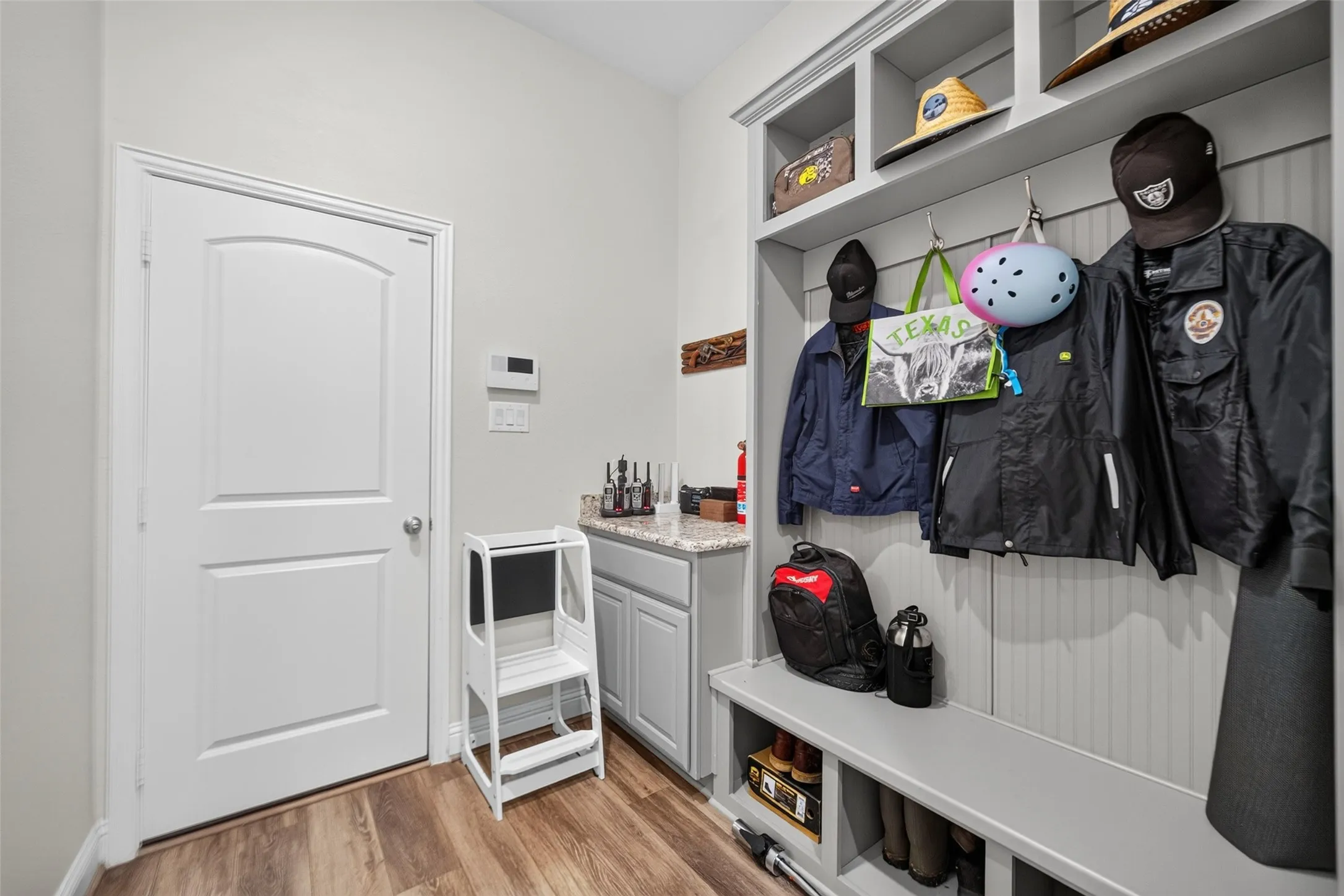 Built-in mudroom storage featuring a bench, upper shelving, and coat hooks