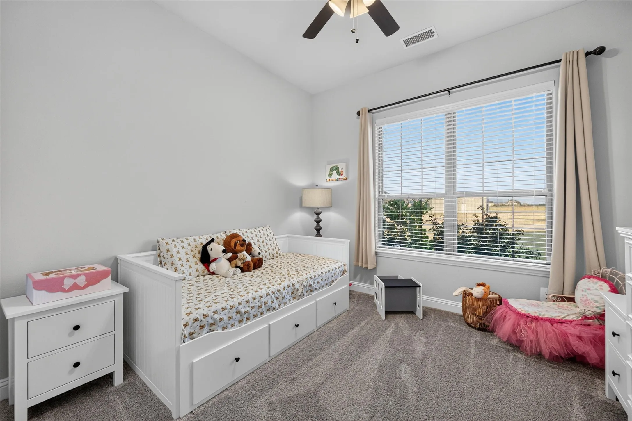 Natural light via a large window, neutral wall paint, ceiling fan, and carpeted flooring