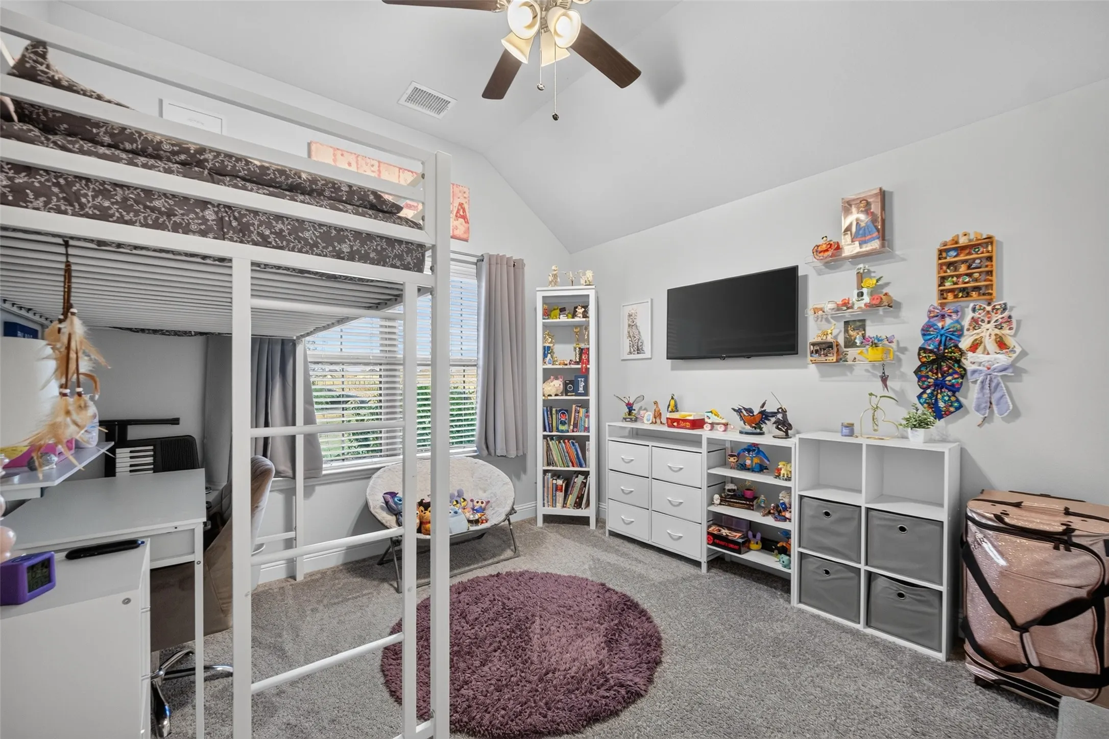 Vaulted ceiling with ceiling fan, wall-mounted television, built-in shelving, carpeted flooring, and window with blinds