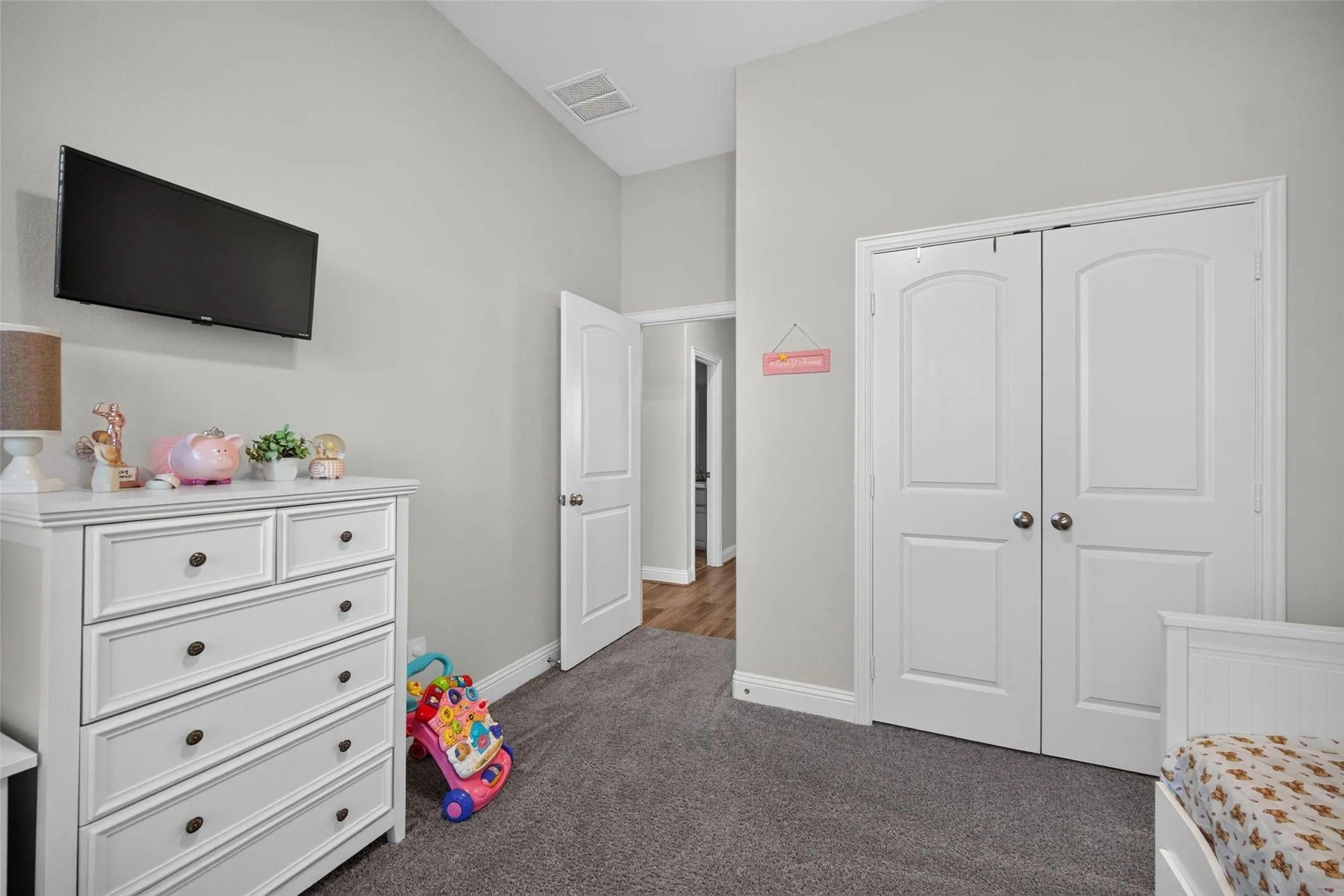 Tray ceiling detail, neutral wall paint, gray carpet, white bi-fold closet doors, and white paneled interior doors