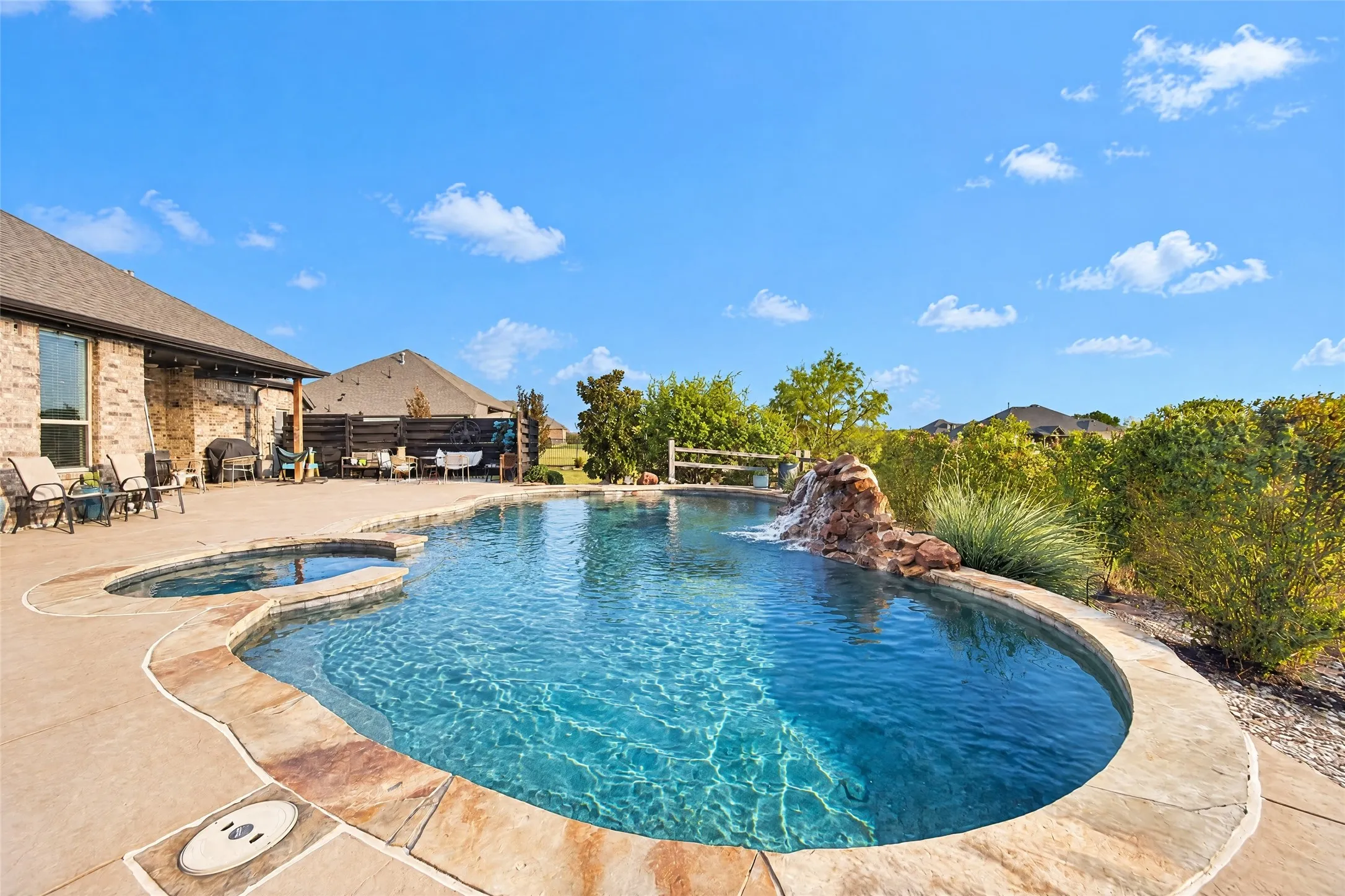 Lagoon-style swimming pool with an integrated spa and rock waterfall feature