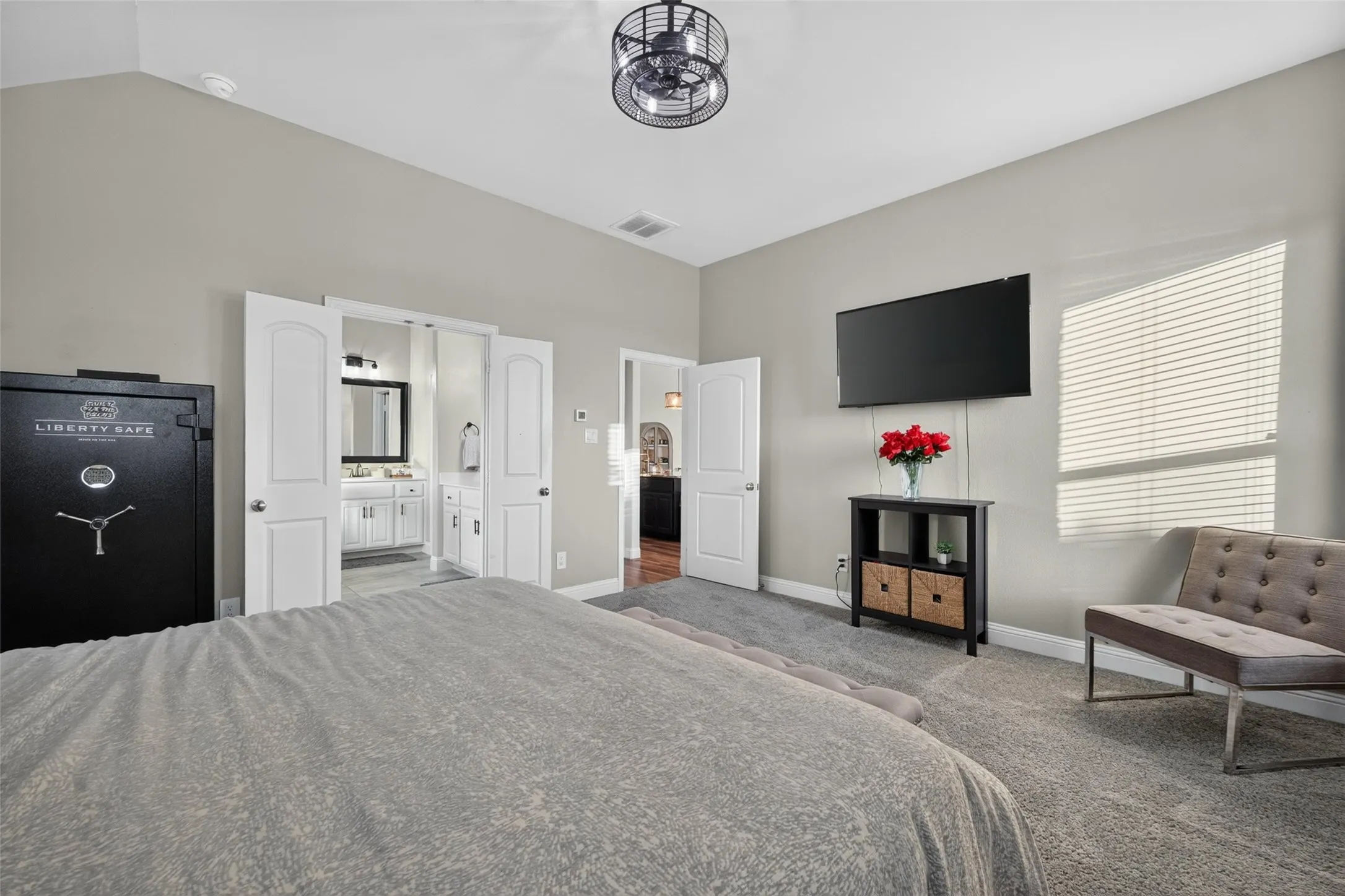 Vaulted ceiling, ceiling fan with integrated lighting, wall-mounted television, window with blinds, and light gray wall paint
