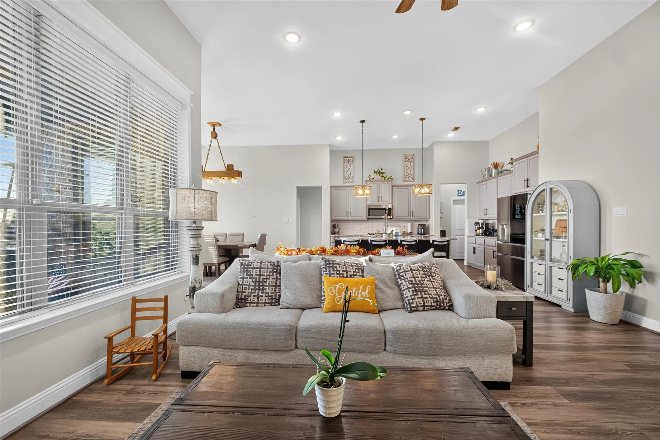 Vaulted ceiling, recessed lighting, wood-finish flooring, large window, and open-concept design