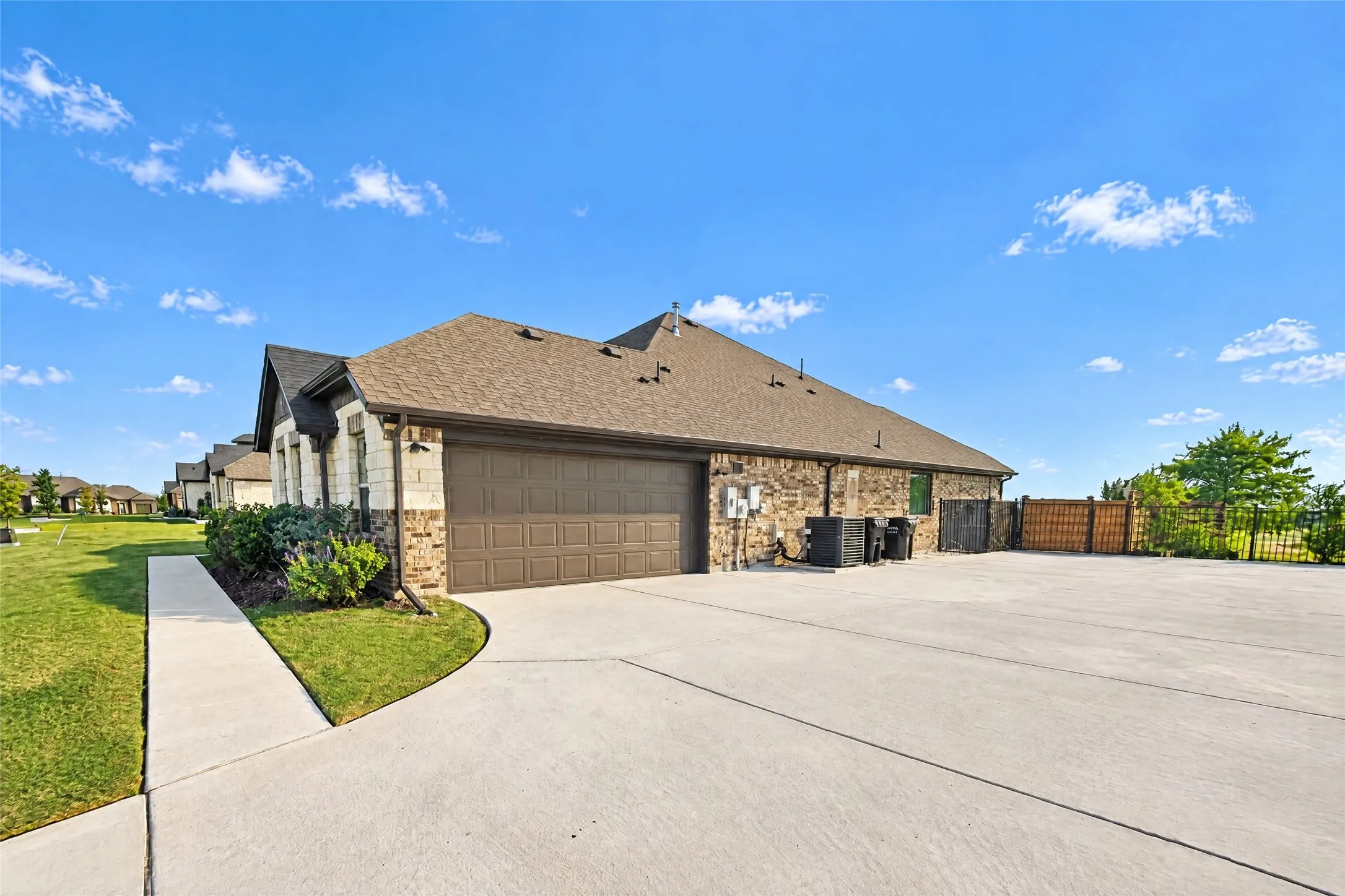 Exterior featuring a stone and brick facade, an attached garage, a concrete driveway, and a concrete pathway