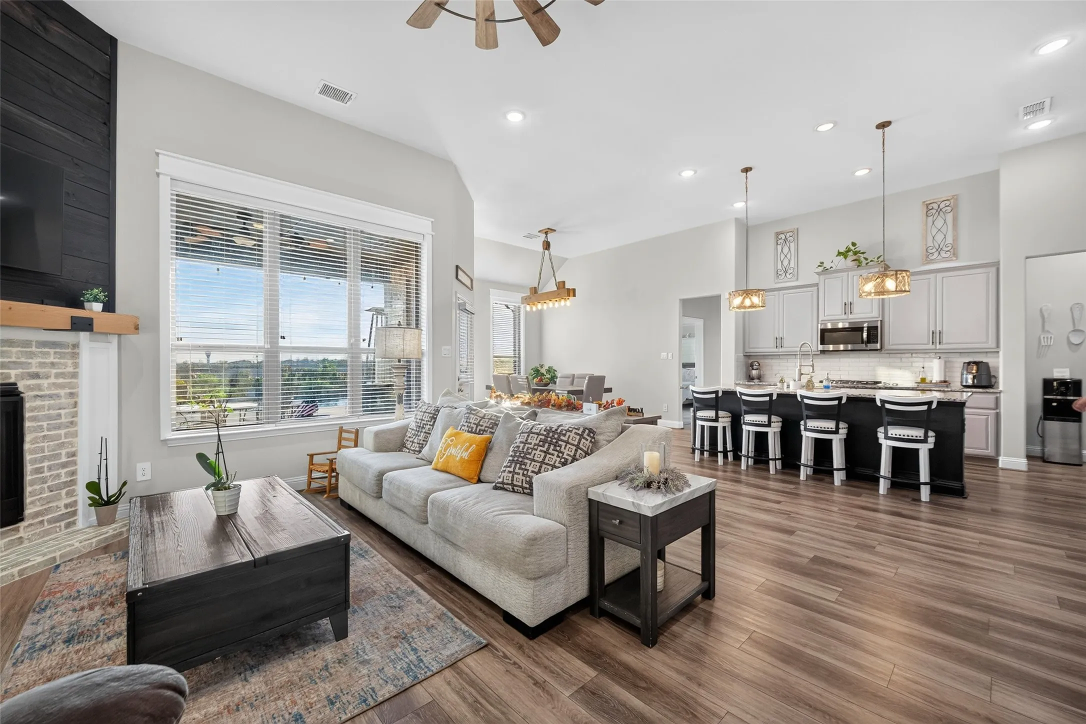Spacious open-concept living area featuring wood-finish flooring, recessed lighting, and a kitchen island with seating