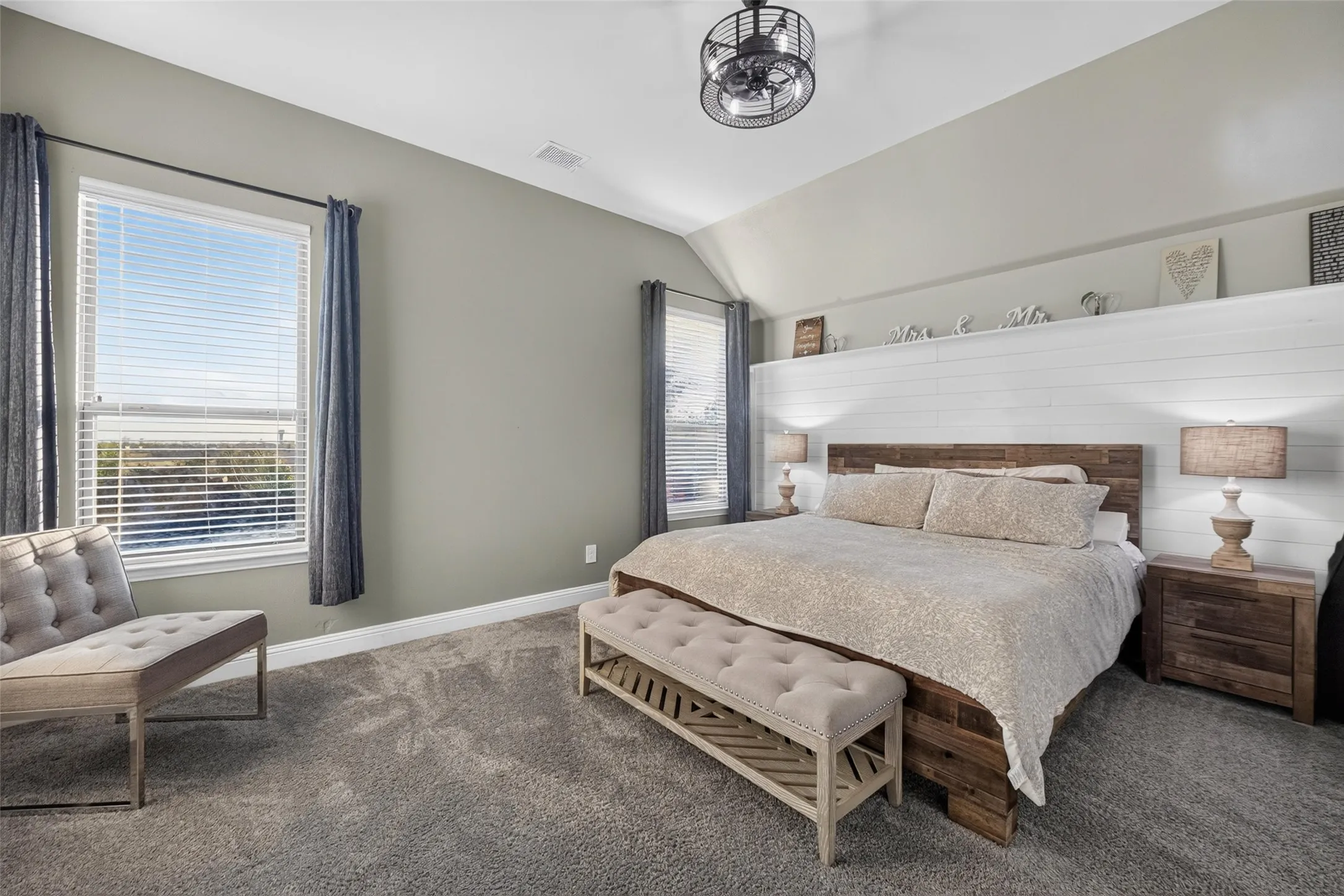 Vaulted ceiling, ceiling fan, carpet flooring, dual windows, and shiplap wall accent