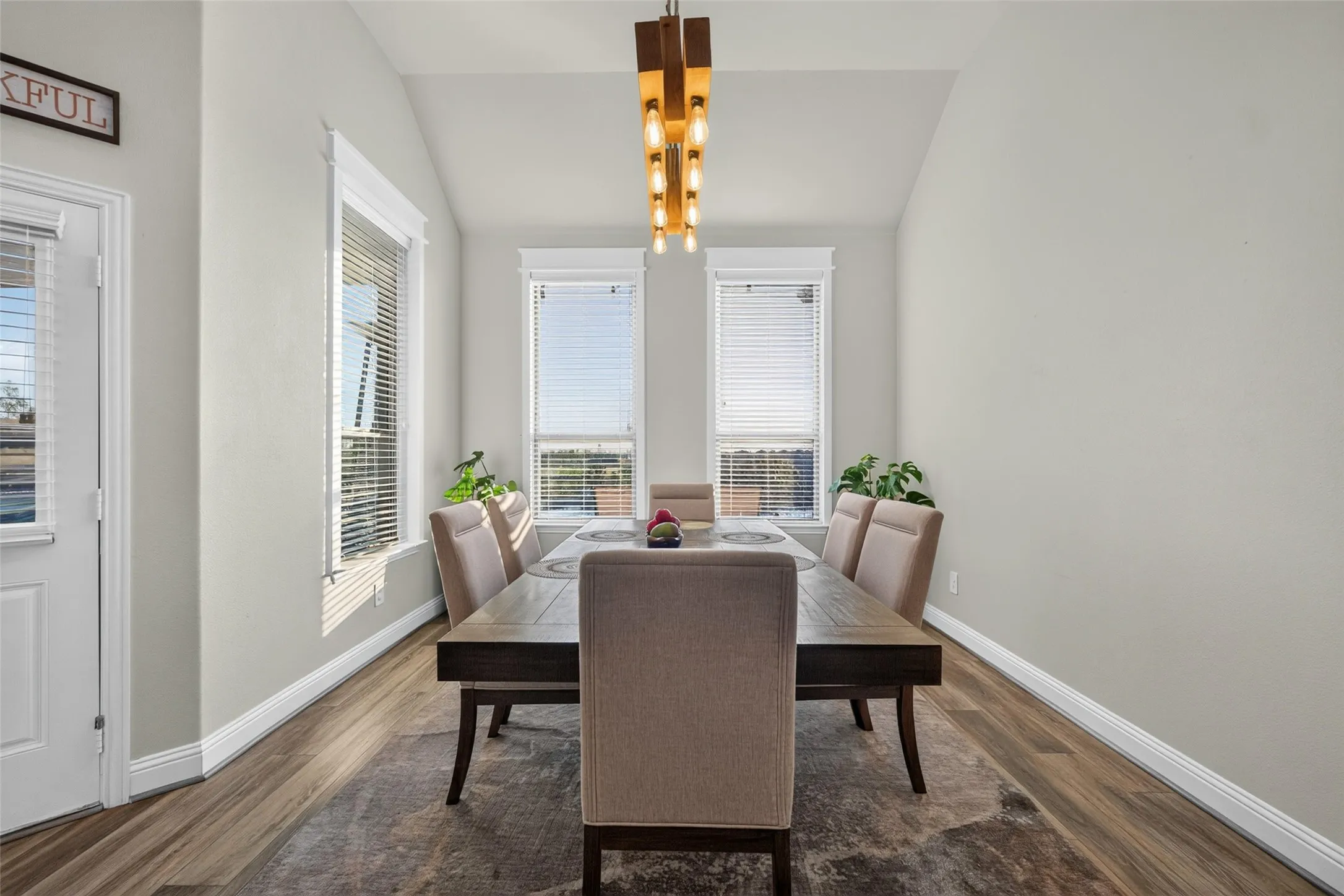Wood-finish flooring, vaulted ceiling, and multiple windows with blinds