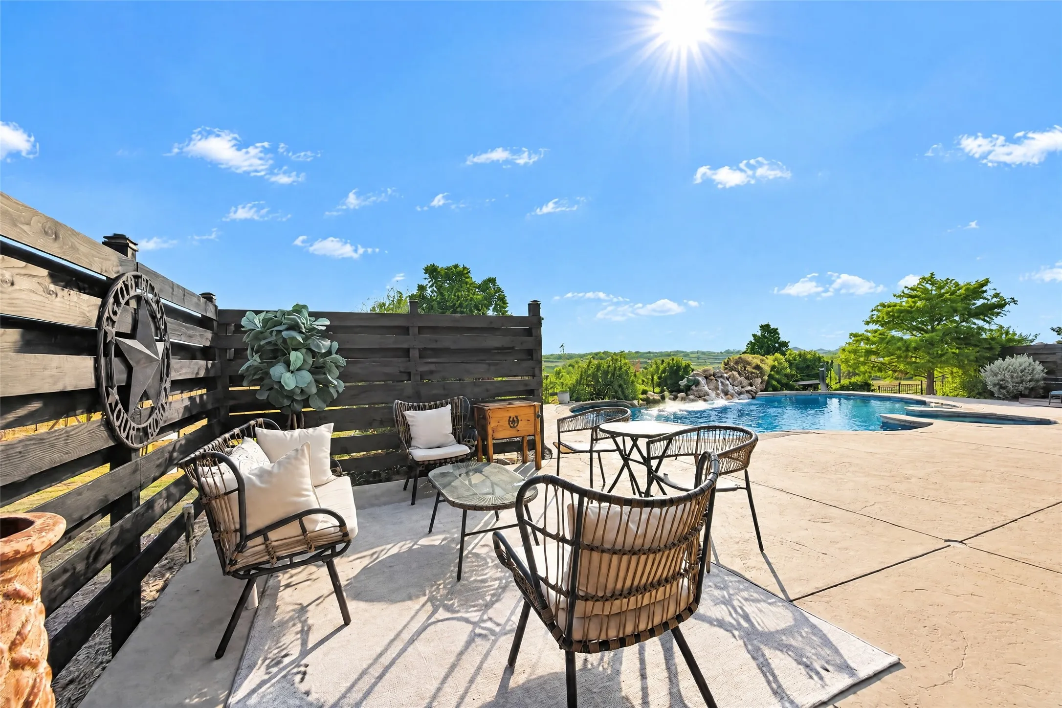 Expansive backyard patio with a concrete surface, featuring a built-in swimming pool with a rock waterfall