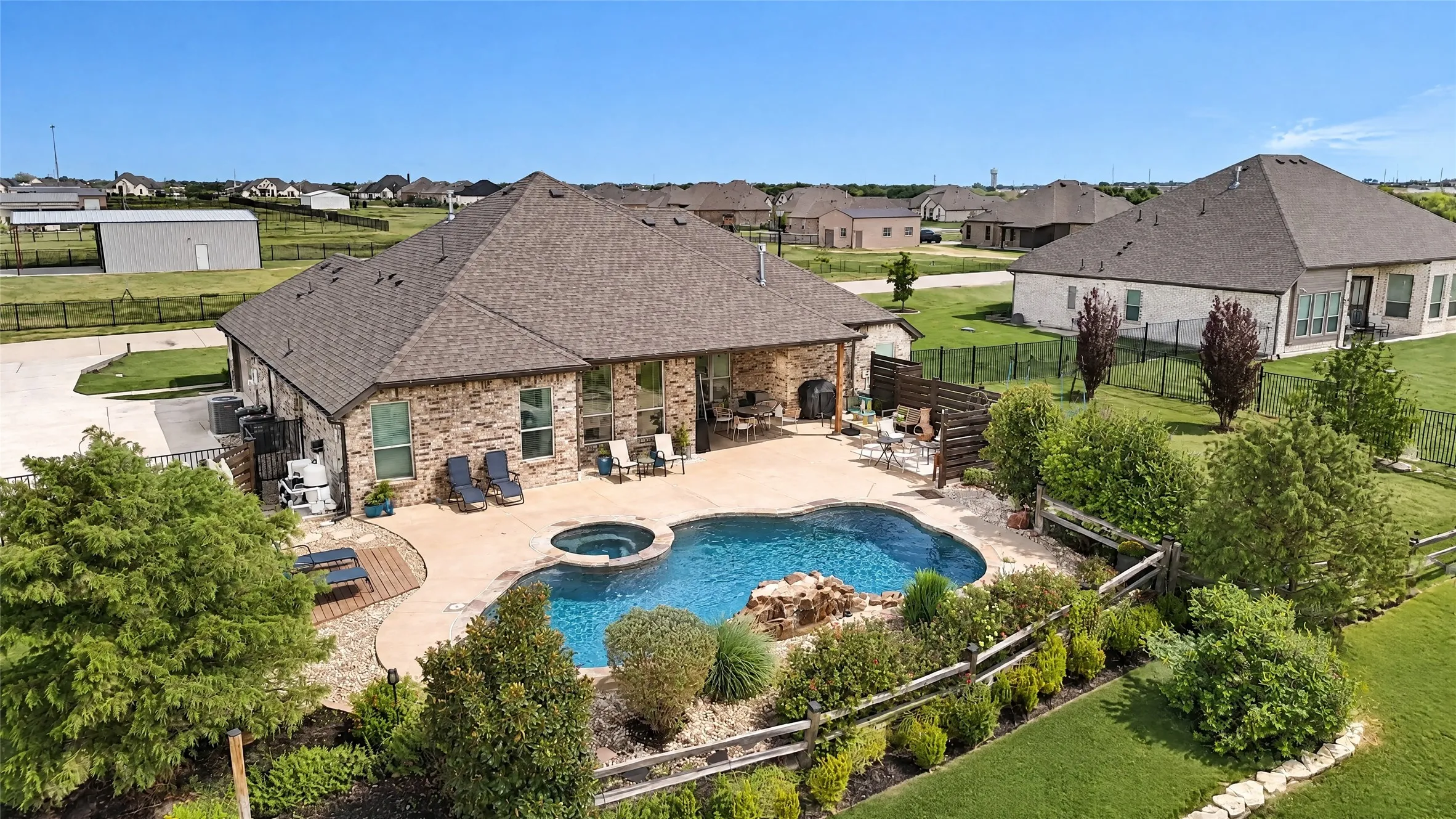 Brick exterior residence with a private swimming pool, integrated hot tub, and an outdoor stone fireplace