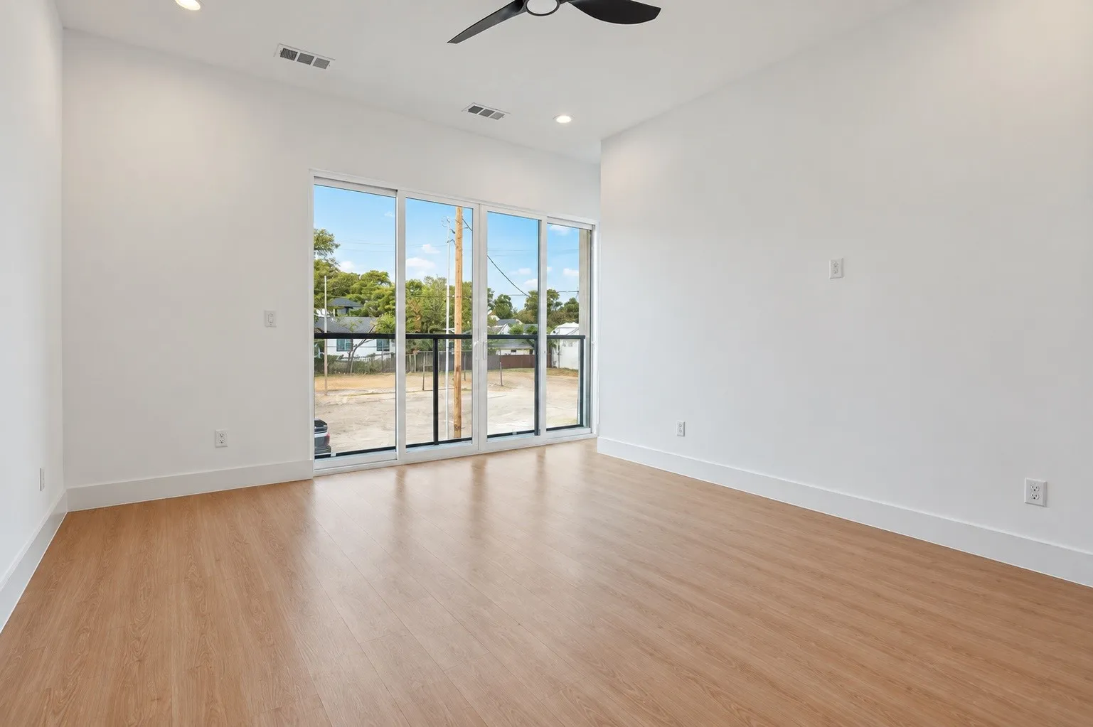 Wood-finish flooring with white walls and a ceiling fan