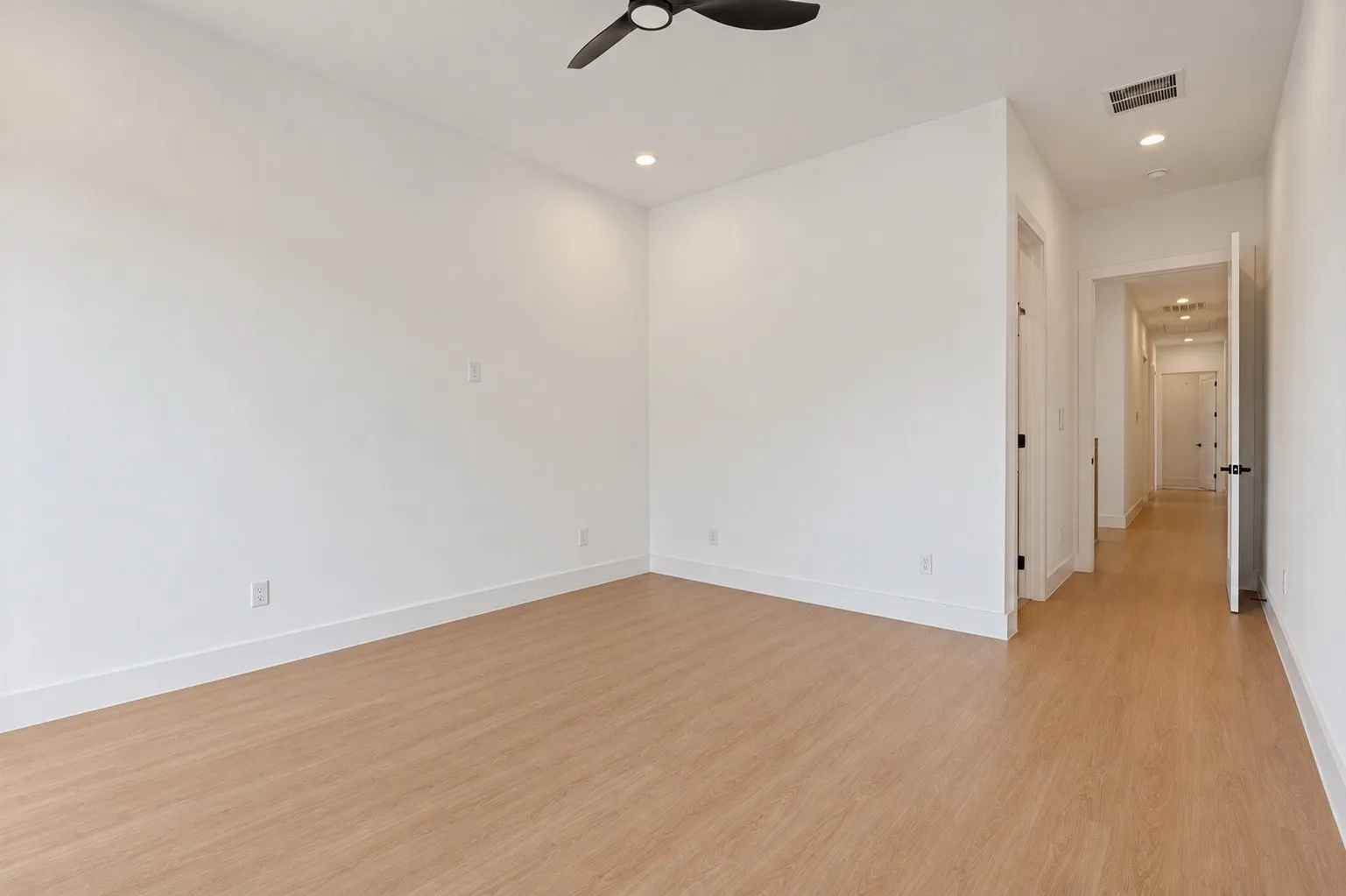 Wood-finish flooring throughout, white walls, recessed ceiling lighting, and a ceiling fan