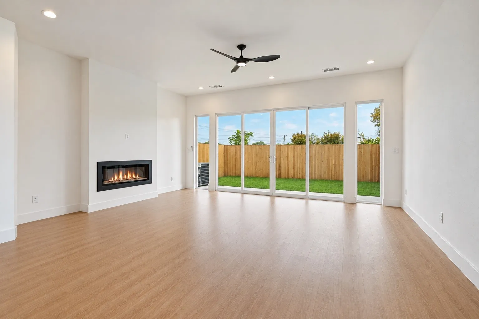 Wood-finish flooring, recessed lighting, and a linear fireplace